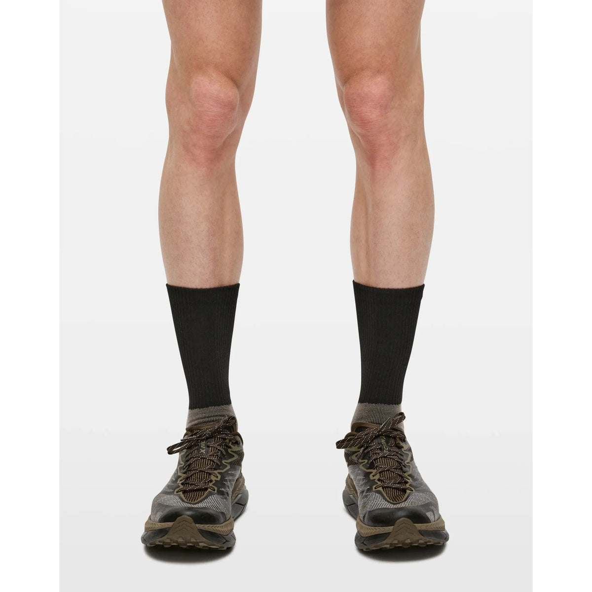 A person wearing Portal Lineage All Purpose Socks in Black Beauty and gray sneakers, shown from the knees down on a neutral background—ideal for versatile, active use.