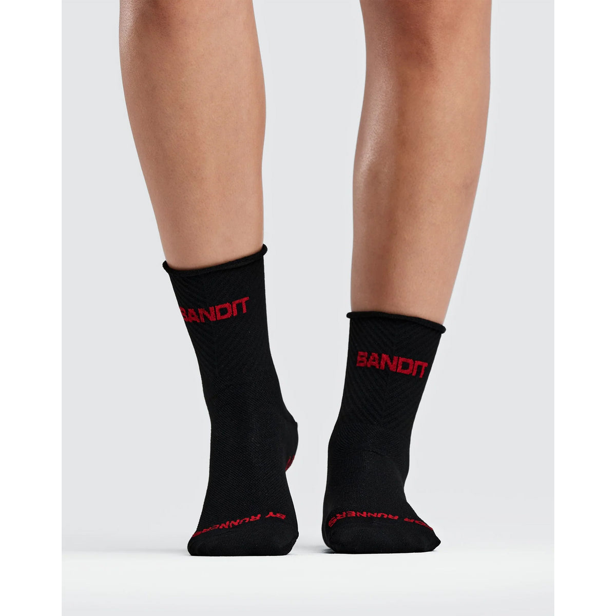 Bandit Lite Run Ribbed 2 Pack Quarter Socks in black with red lettering on the cuffs and toes, worn on lower legs.