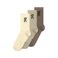 Three pairs of On Logo Socks High in Hare and Brume—a pack featuring cream, light beige, and brown shades—are displayed side by side. Each sock has a distinctive black “oc” logo near the top and branding near the toe. Designed as versatile running socks, they deliver all-day comfort and gentle arch support for whatever your day holds.
