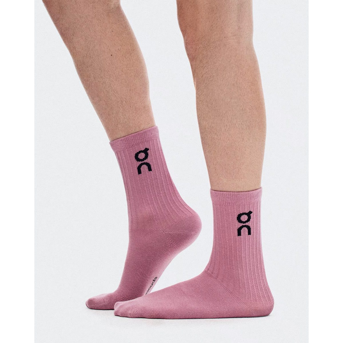 Two legs wearing On Logo Socks High in Sherbet/Rhodonite—a pink crew sock featuring a black logo on the side—stand on a plain white background. These socks deliver versatile, all-day comfort and arch support, making them ideal for any activity.