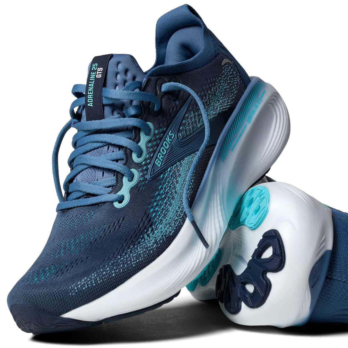 A pair of blue Brooks running shoes with teal accents and white soles, one shoe standing upright and the other lying on its side, showcasing the tread pattern.