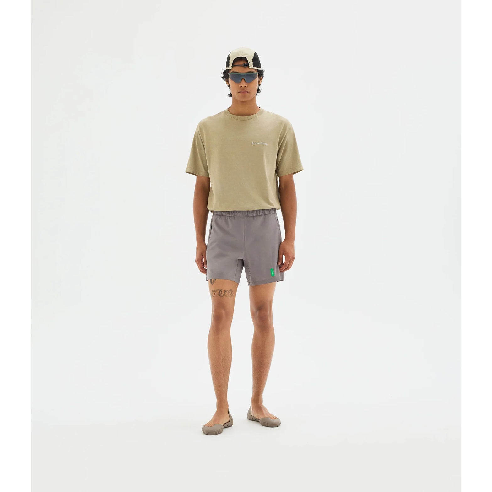 District Vision Men's 7 Inch Training Shorts Carbon full body view on male runner showing ultralight liner with dual zippered side pockets and rear envelope pocket for comprehensive storage