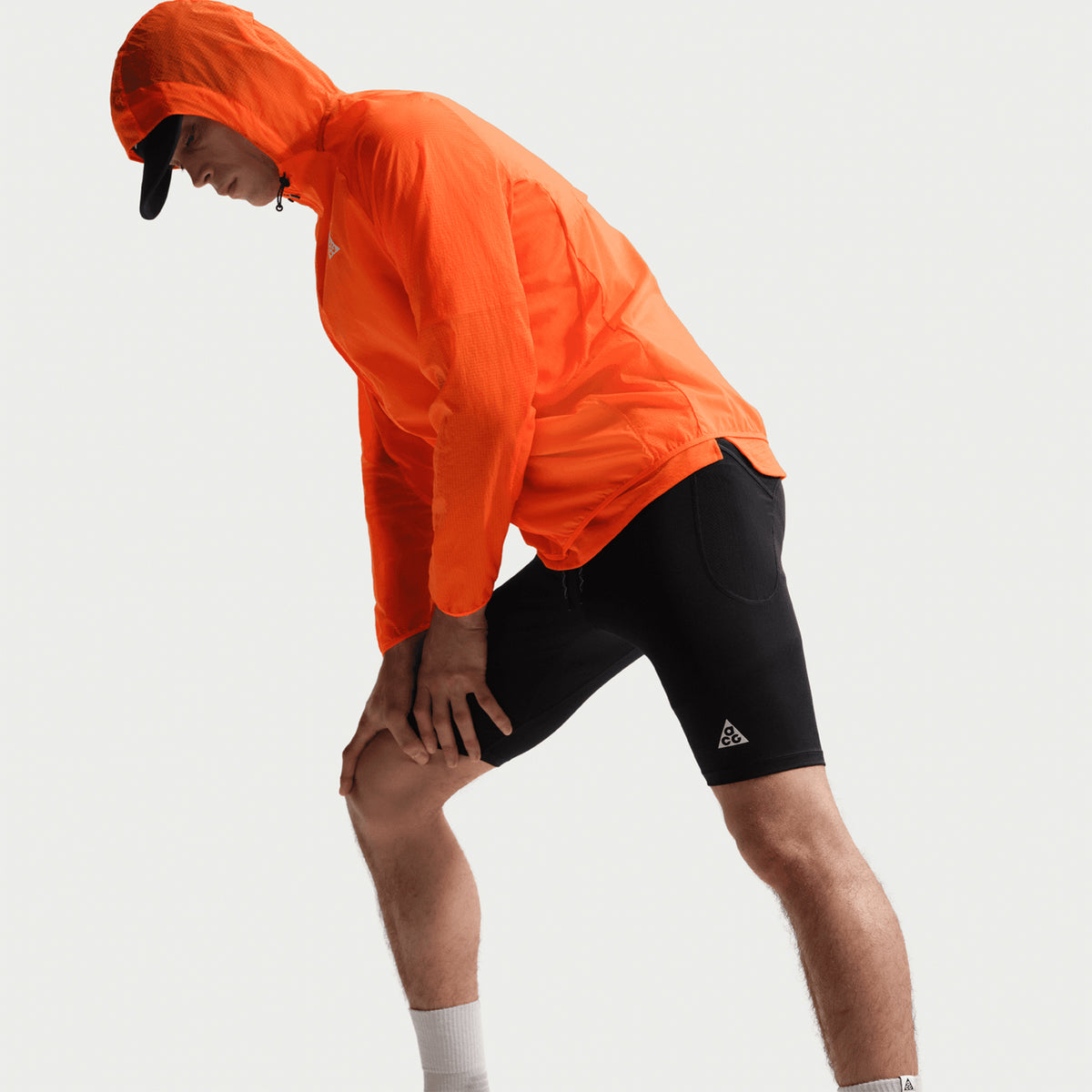 Men's Nike ACG Dri-FIT ADV Half Tights Black Summit White side view on male runner stretching showing smooth stretchy fabric, locked-in fit and freedom of movement for trail running