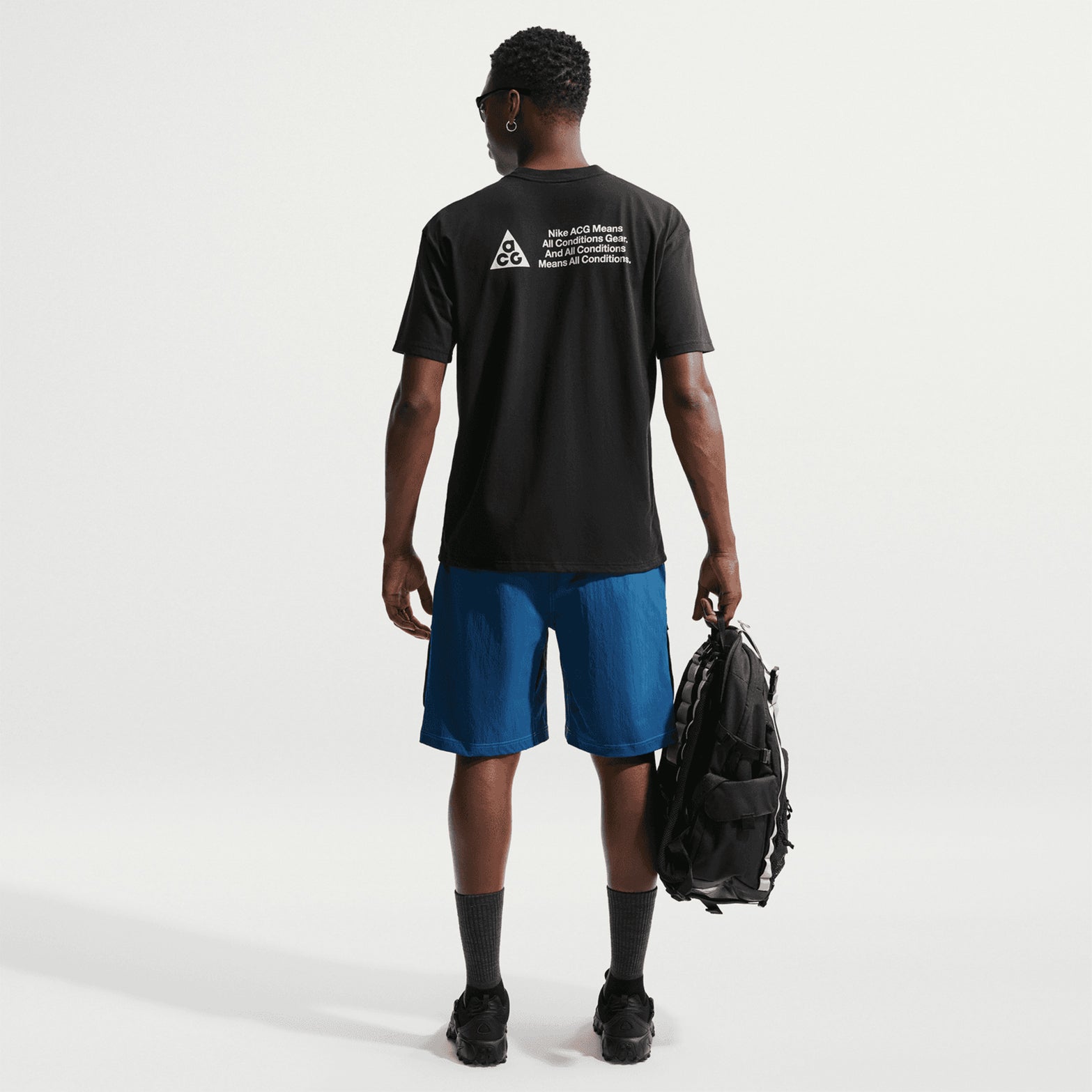 Men's Nike ACG Dri-FIT T-Shirt Black full body back view on male model showing ACG All Conditions Gear bold text print and cotton-polyester blend fabric