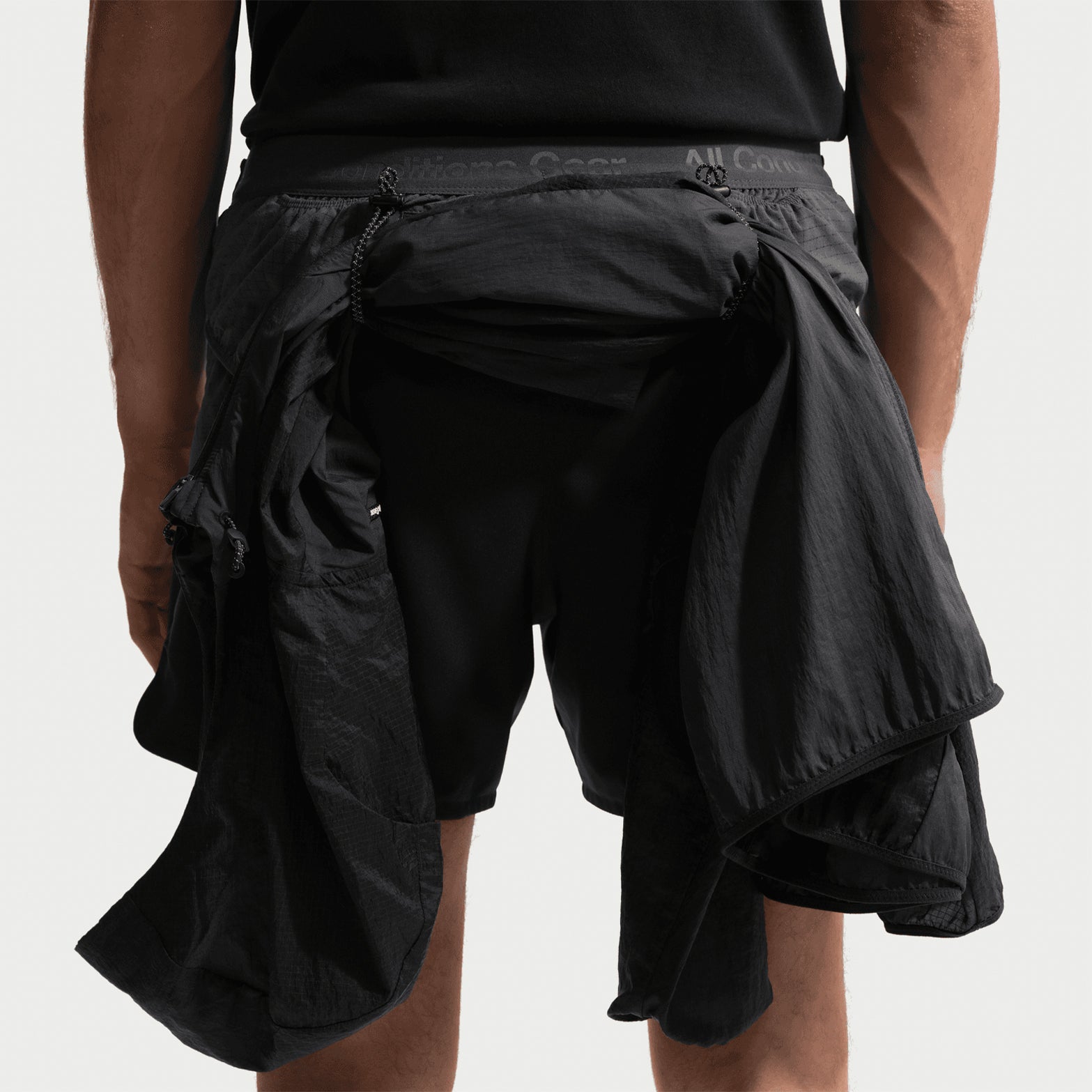 Men's Nike ACG Second Sunrise Dri-FIT 5 Inch Running Shorts Black Anthracite Summit White back view showing jacket looped through back loops designed for trekking poles or gear storage during trail running and hiking