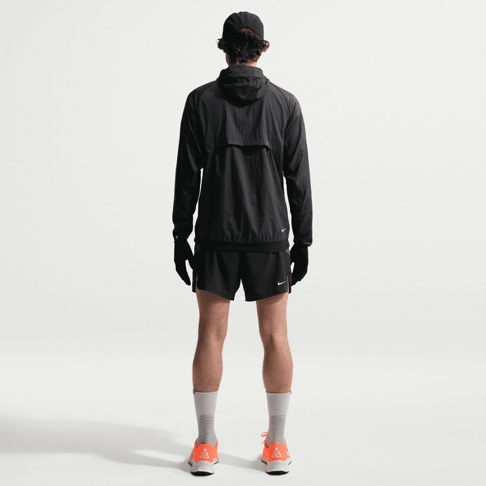 Men's Nike ACG Second Sunrise Dri-FIT 5 Inch Running Shorts Black Anthracite Summit White full body back view on male trail runner showing zippered phone pocket, trekking pole loops and reflective ACG branding with Dri-FIT ADV construction for long-distance trails