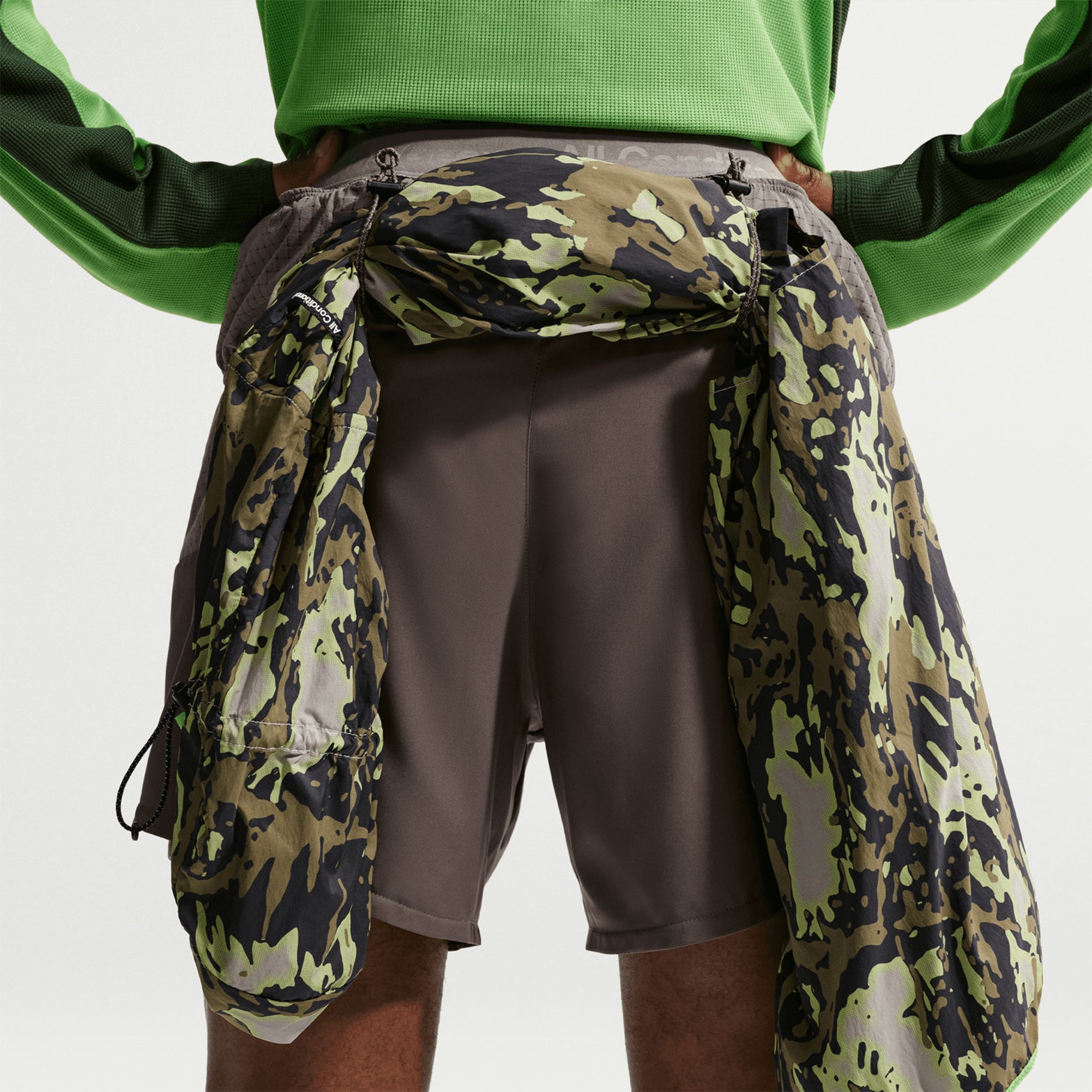 Men's Nike ACG Second Sunrise Dri-FIT 5 Inch Running Shorts Ironstone Cave Stone Summit White back view showing jacket looped through back loops designed for trekking poles or gear storage during trail running and hiking