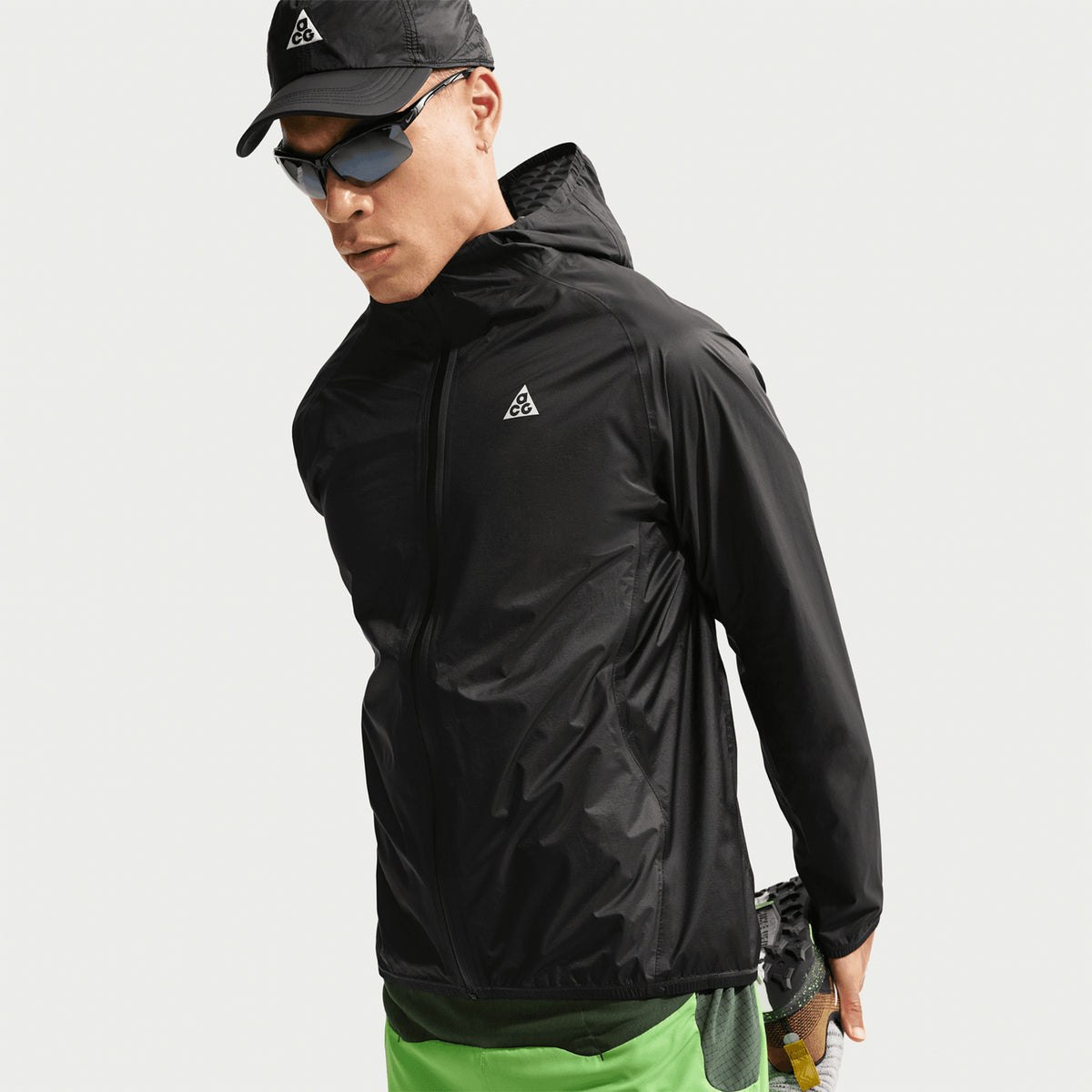 Nike ACG Trailwind men's Storm-FIT ADV jacket in Anthracite / Summit White — side view worn on model showing anthracite ultra-lightweight nylon, bungee-adjustable hood and reflective logos for trail weather protection