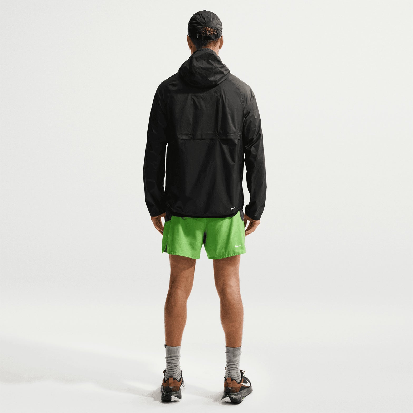 Nike ACG Trailwind men's Storm-FIT ADV jacket in Anthracite / Summit White — full body back view worn on model showing anthracite sealed seams, back vents for breathability and interior back pocket for packable storage