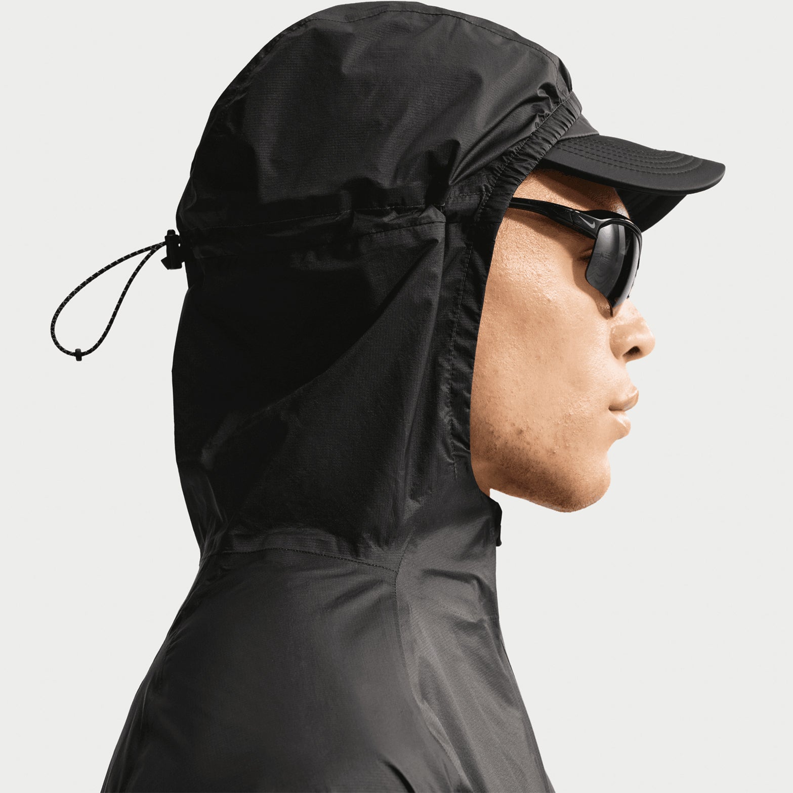 Nike ACG Trailwind men's Storm-FIT ADV jacket in Anthracite / Summit White — closeup showing bungee-adjustable hood detail with summit white drawcord and anthracite nylon construction for customisable coverage