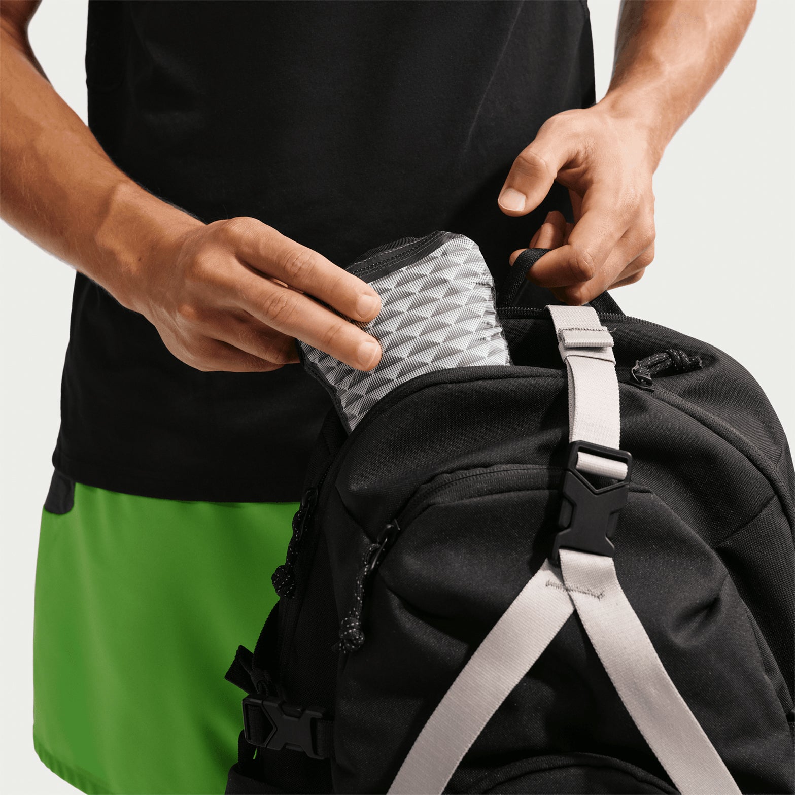 Nike ACG Trailwind men's Storm-FIT ADV jacket in Anthracite / Summit White — jacket packed into interior back pocket showing anthracite ultra-lightweight nylon compacted for packable storage and easy carrying
