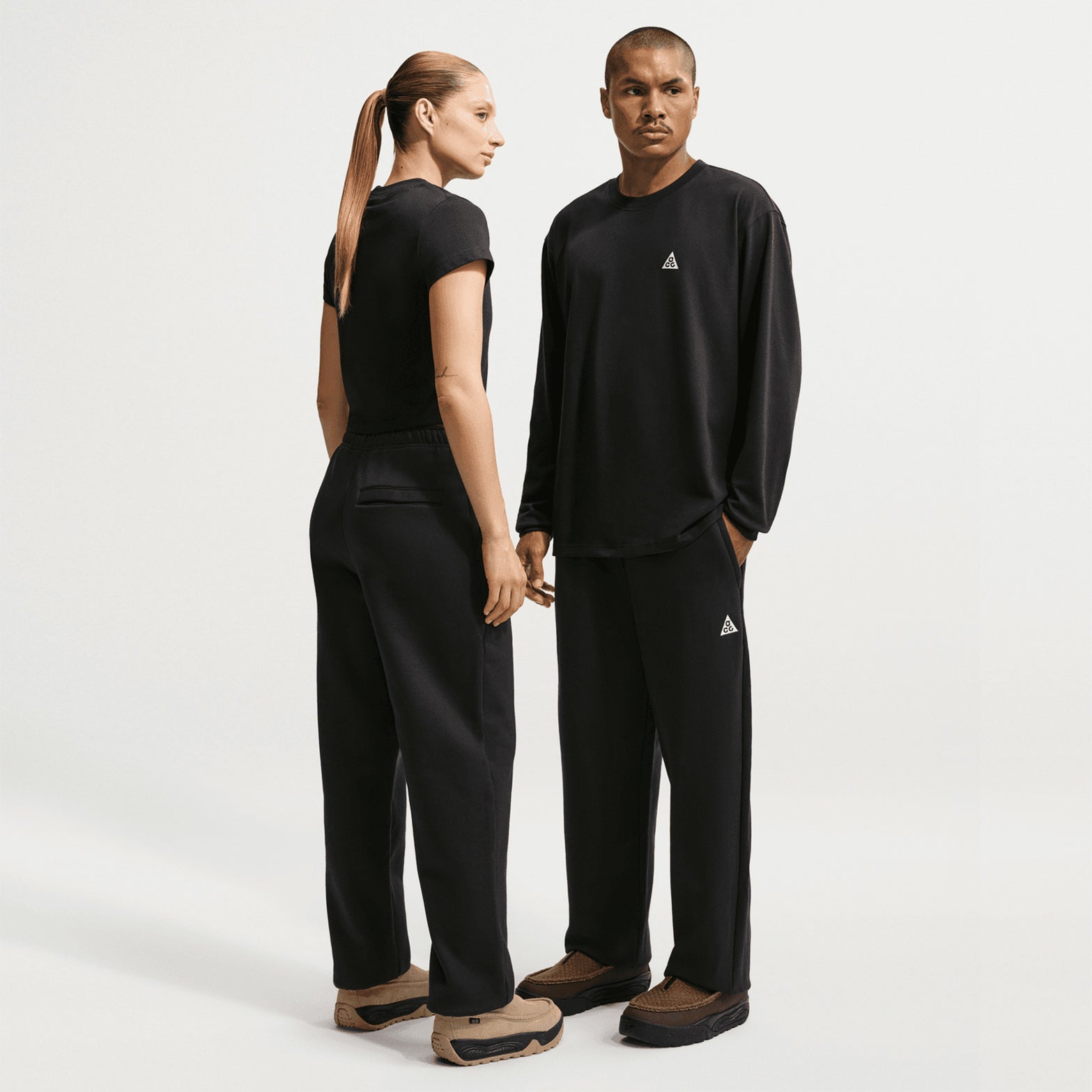 Nike ACG Tuff Fleece trousers in Black / Summit White — full body view worn on female model showing black durable Tuff Fleece construction with summit white accent and practical pocket placement