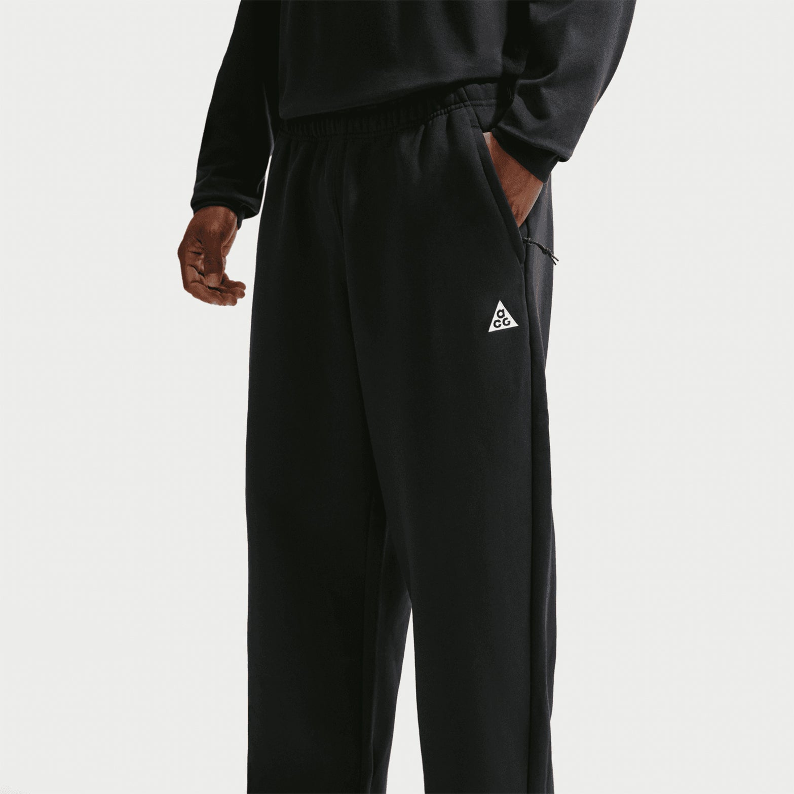 Nike ACG Tuff Fleece trousers in Black / Summit White — side product shot showing black Therma-FIT fleece construction, elastic cuff and practical locker loop detail