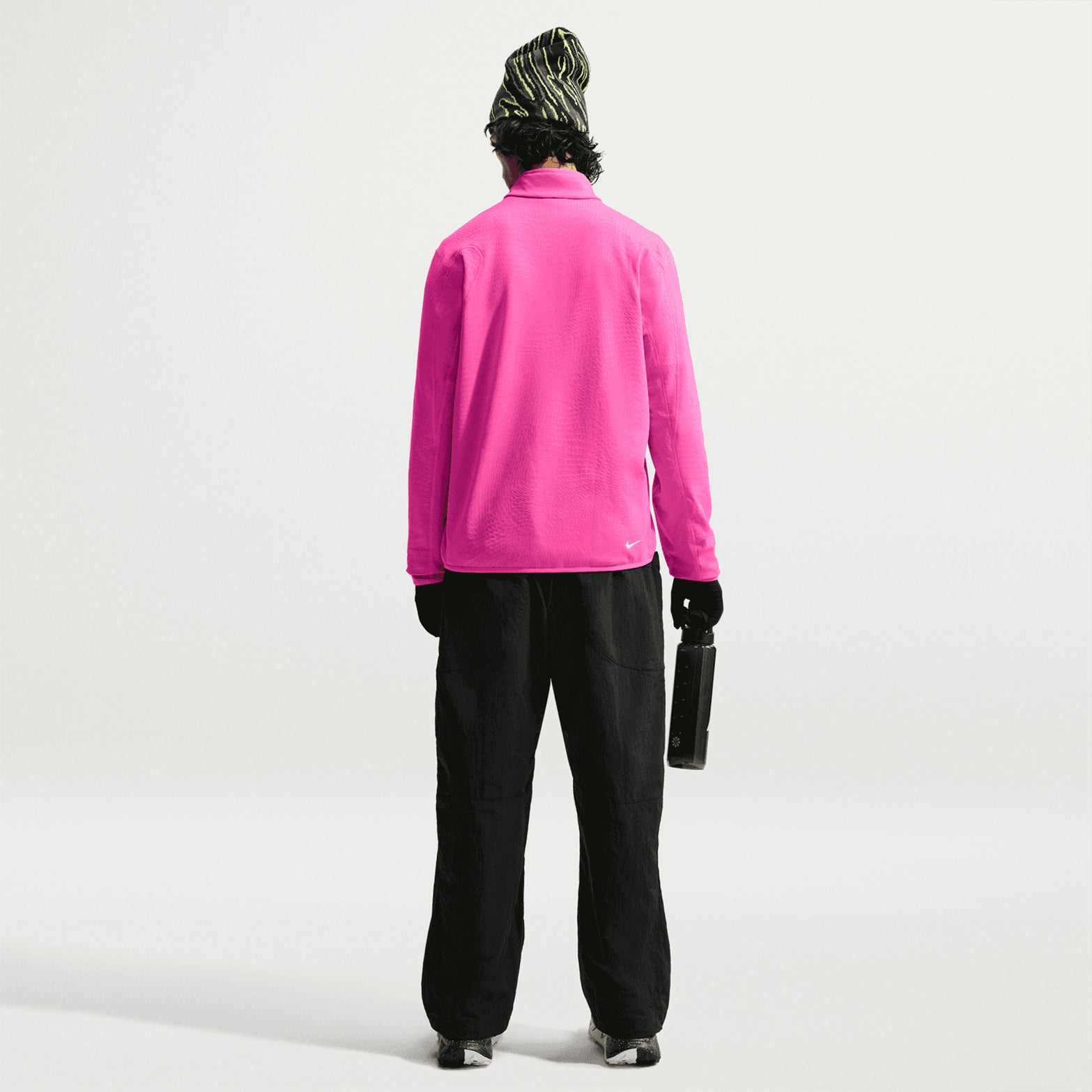 Men's Nike ACG Wolf Grid Therma-FIT 1/2 Zip Top Desert Pink Light Crimson Summit White full body back view on male trail runner showing grid-back fleece with Therma-FIT technology, flat seam shoulder panels and elastic hem for warmth and breathability during outdoor adventures