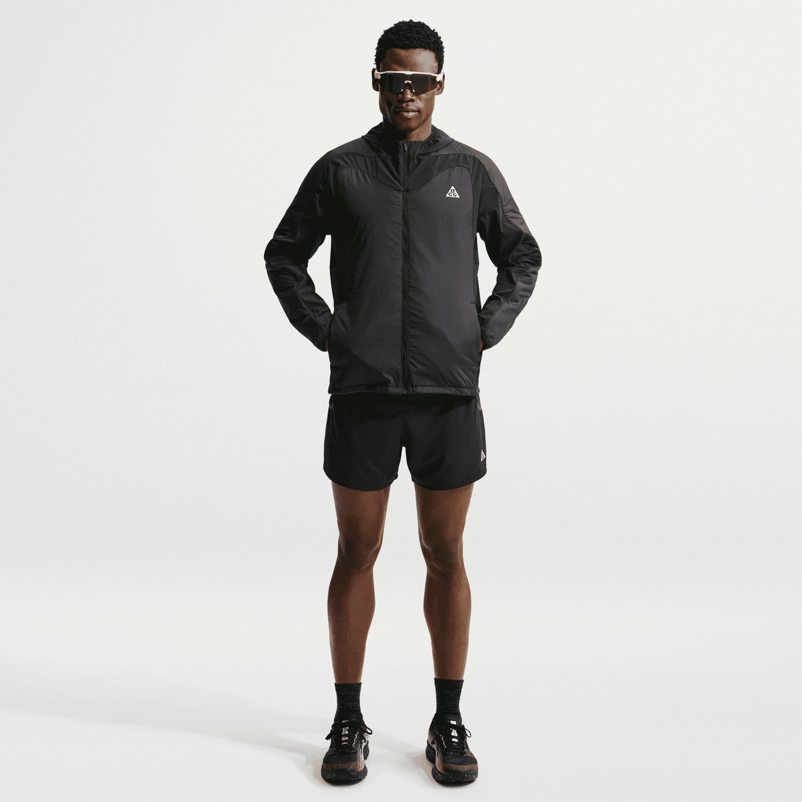Men's Nike ACG Rope de Dope Jacket Black Summit White front view on male runner showing Therma-FIT ADV heat-regulating construction with bungee drawcord hem and multiple pockets for cold weather outdoor use