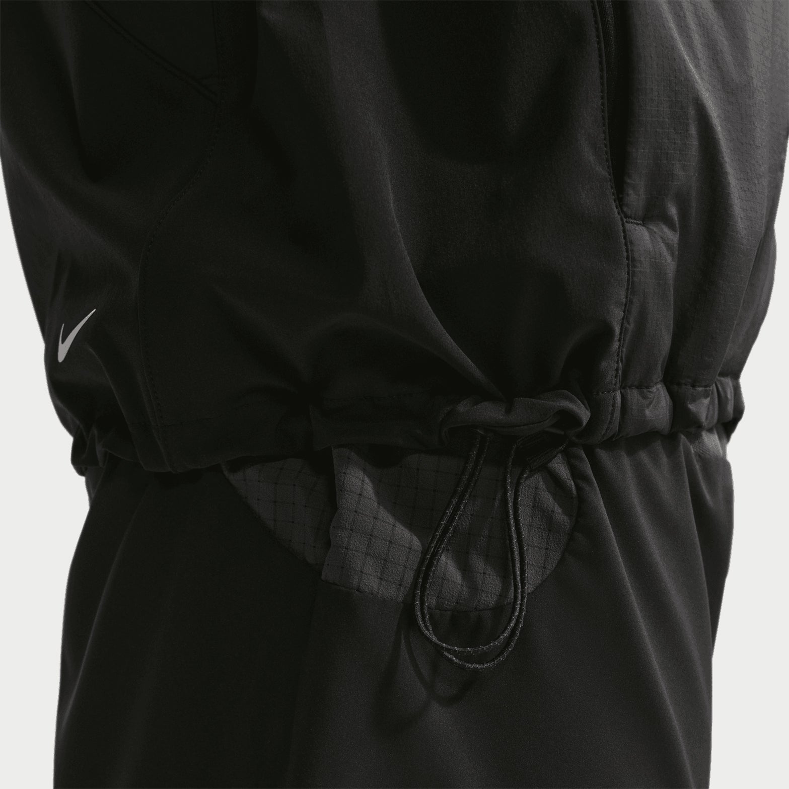 Men's Nike ACG Rope de Dope Jacket Black Summit White close-up of bungee and drawcord hem showing adjustable fit system for sealing warmth and customising coverage during cold weather outdoor activities