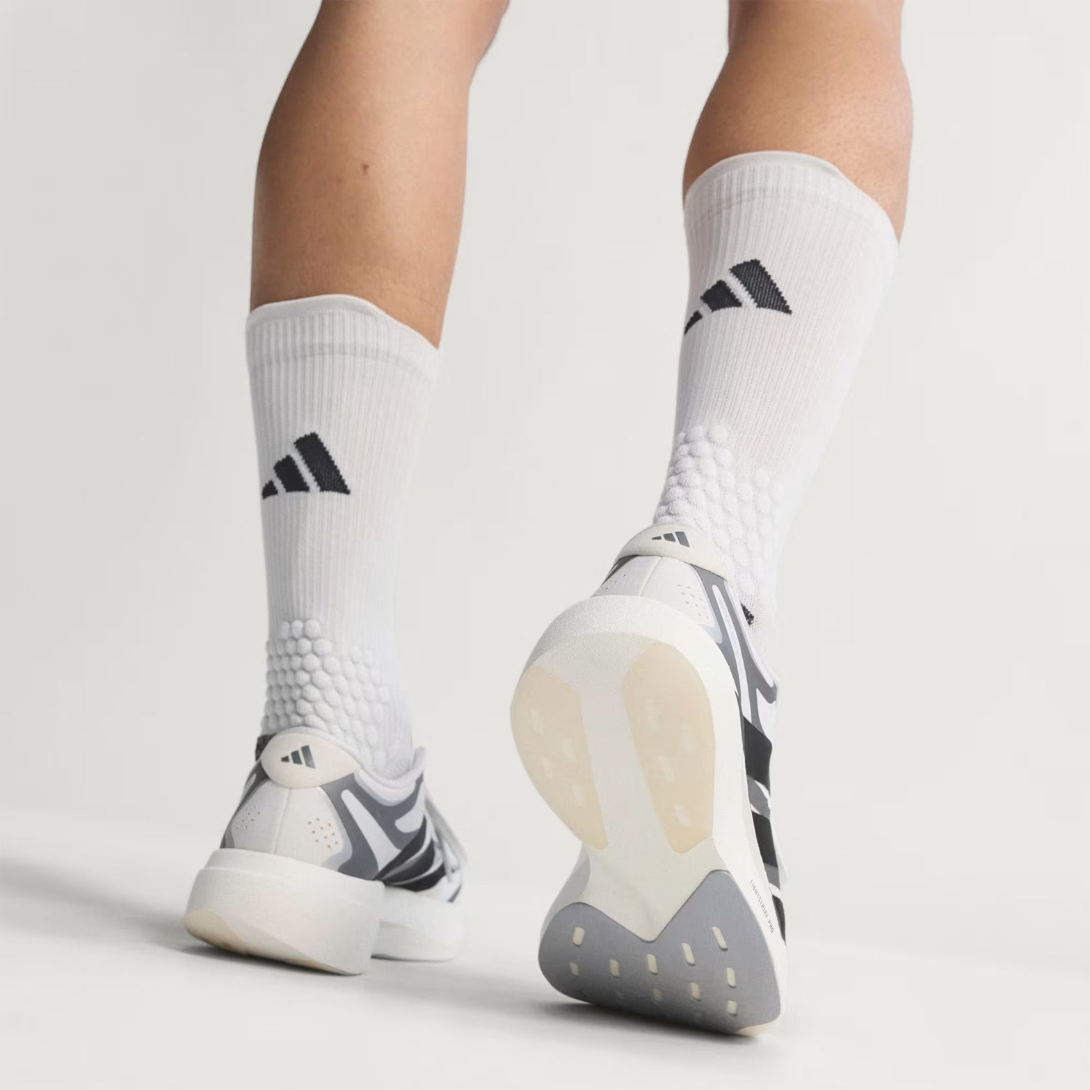 adidas Adizero EVO SL EXO men's running shoe in Cloud White / Core Black / Iron Metallic — outsole view showing sculpted rubber tread pattern and iron metallic LightstrikePro super-light midsole profile