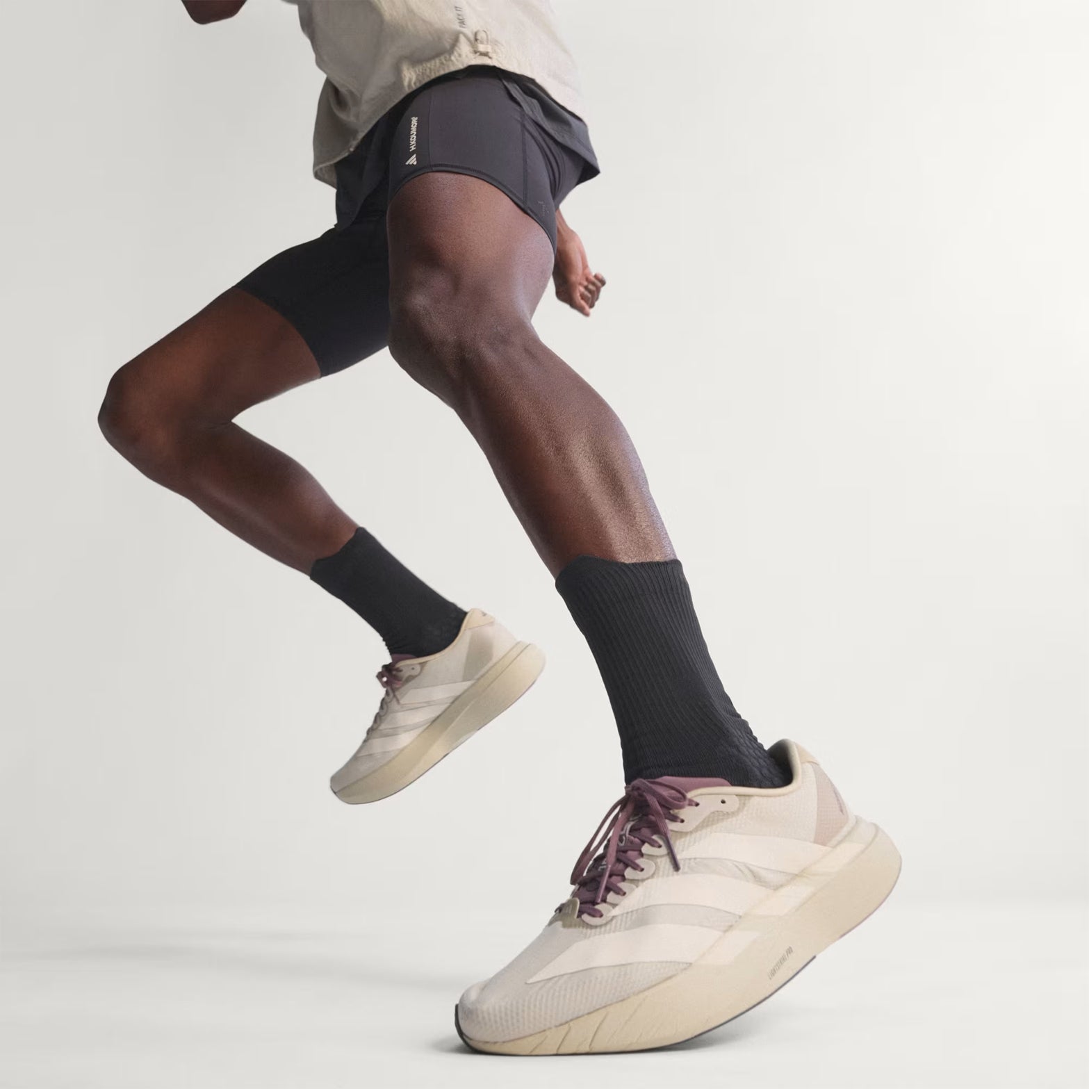 Men's Adizero EVO SL Woven H.Koumori Running Shoes Putty Grey Alumina Shadow Fig side view on model stepping up demonstrating flexibility