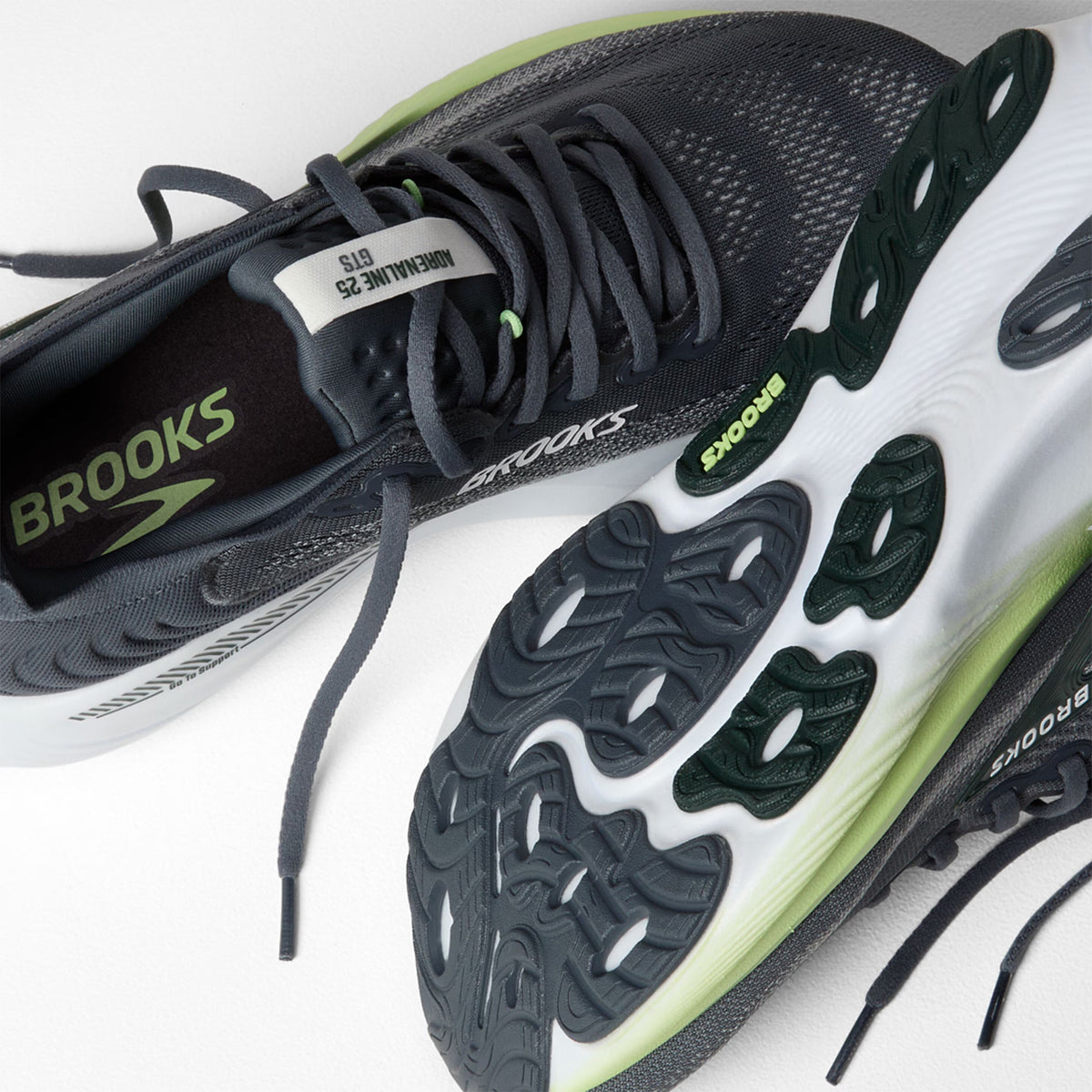 Brooks Adrenaline GTS 25 men's running shoe in Grey / Paradise Green / Spruce — angled side view showing grey engineered mesh upper, GuideRails support sidewalls and paradise green DNA LOFT cushioning midsole stack