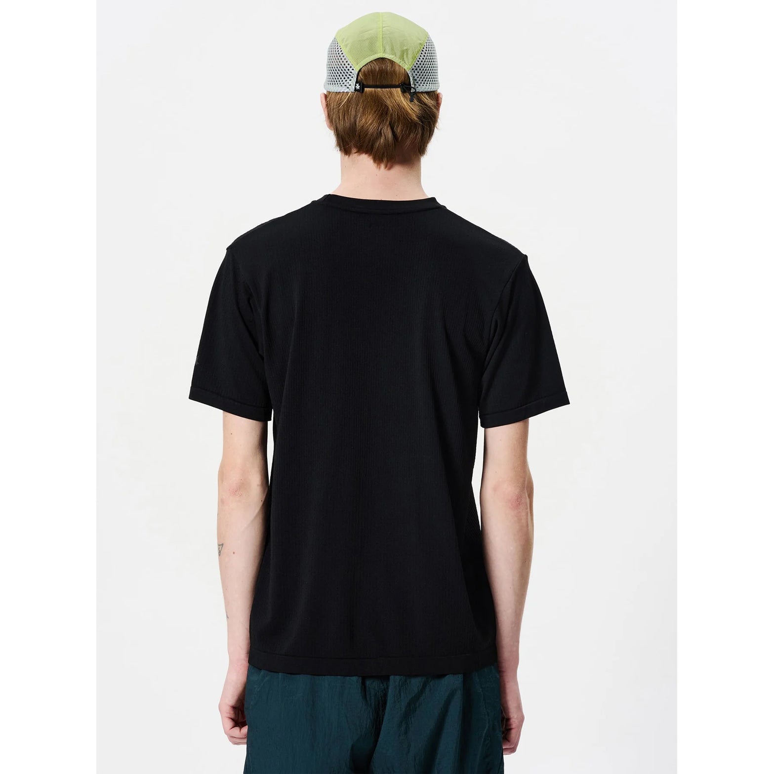 Goldwin Men's Convexity Dry Teeback view on male model showing dual-layer construction with nylon inner and polyester outer for moisture distribution