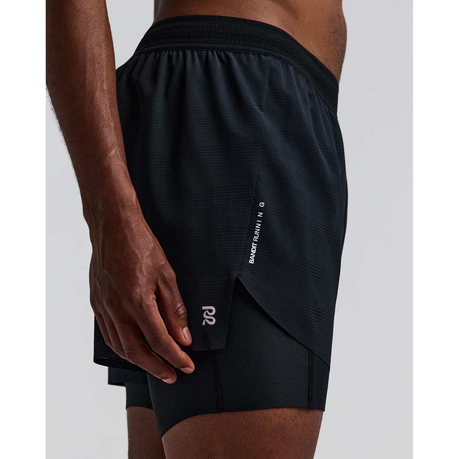 Men's Bandit CoolGrid 2-in-1 Run Short Black side view on male runner showing CoolGrid breathable outer with GripDot hems and waterproof leg pocket for comfortable running and racing