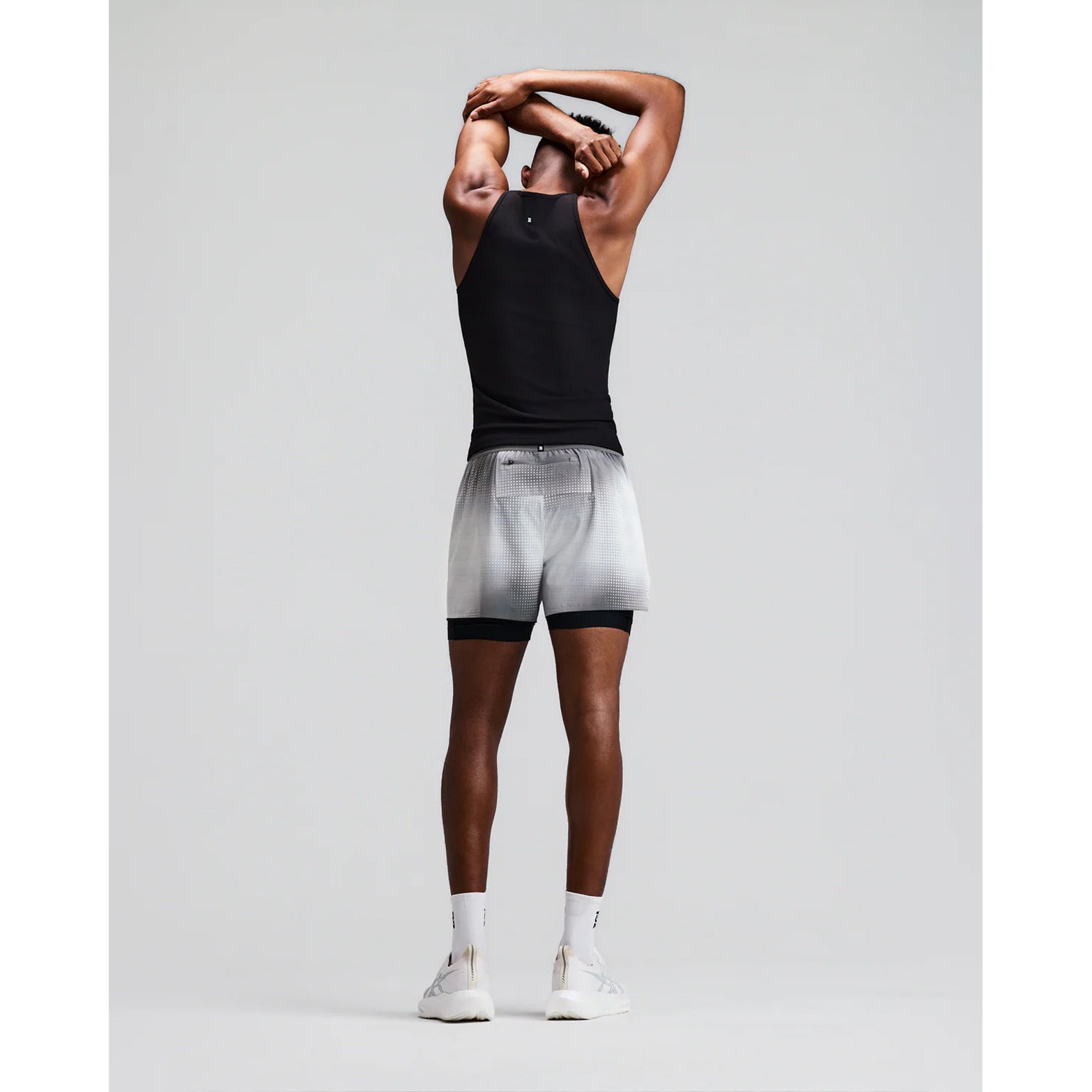Men's Bandit CoolGrid 2-in-1 Run Short Micro Geo Gradient Slate Plaster back full body view on male runner showing GripDot hem grip with reflective centre back branding and Micro Geo Gradient CoolGrid breathable construction