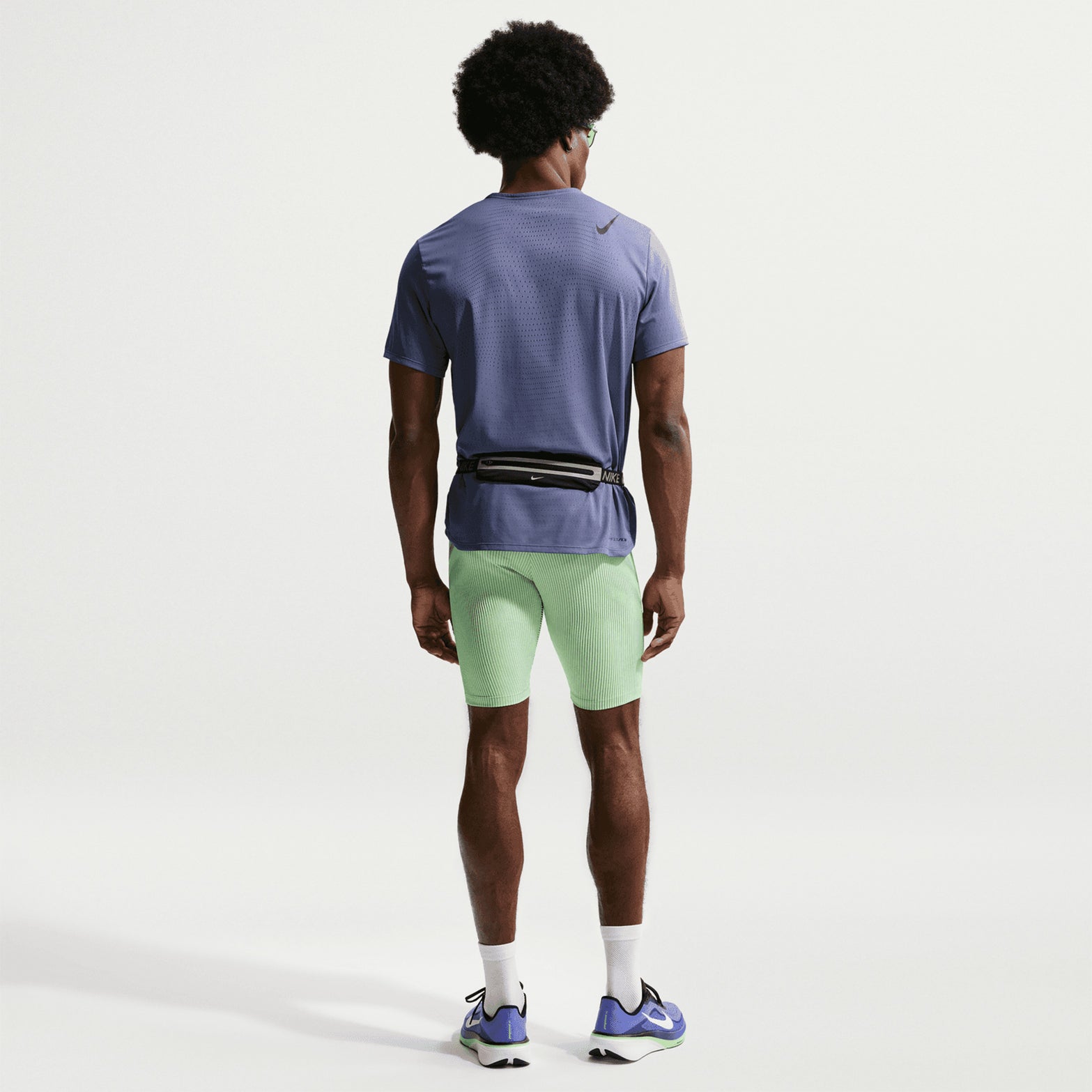 Men's Nike Dri-FIT AeroSwift ADV Half Tights Green full body back view on male runner showing zippered phone pocket, waist pockets and streamlined racing design