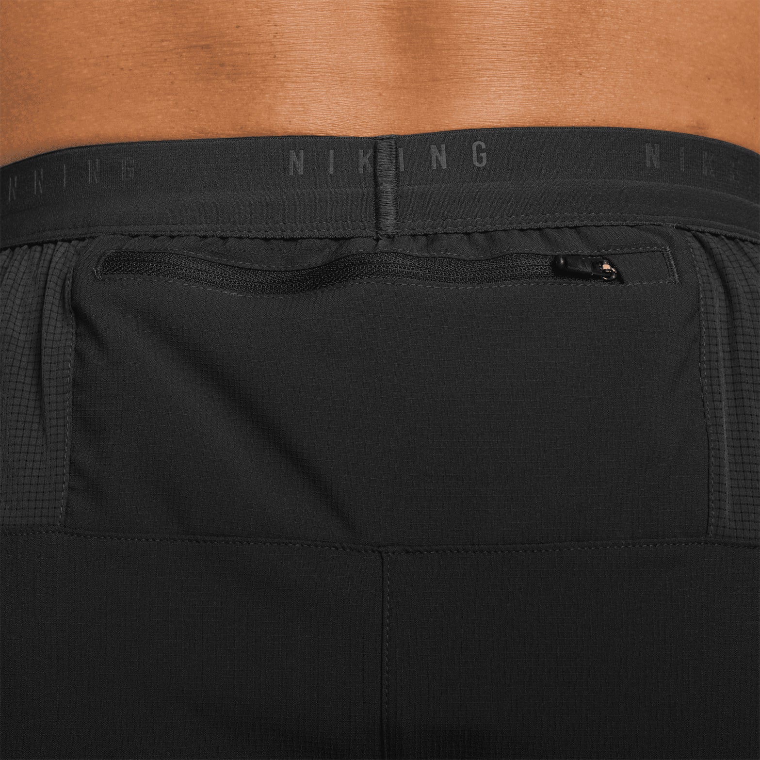 Men's Nike Dri-FIT Stride 5 Inch Shorts Black close-up of zippered back pocket showing secure phone storage with internal moisture barrier to protect device from sweat