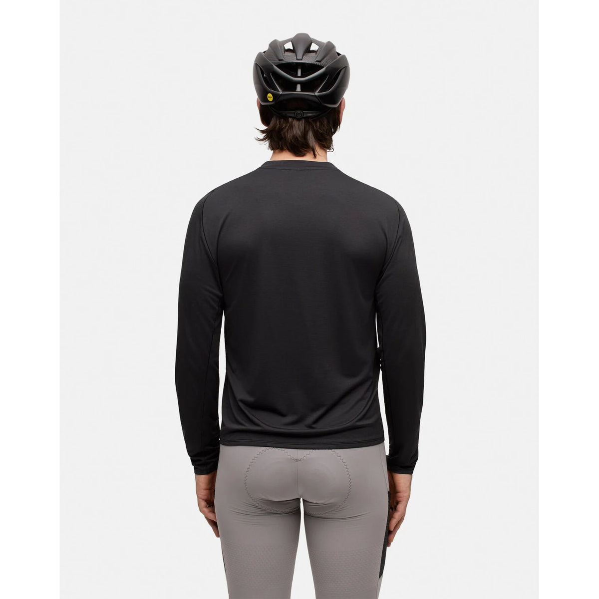A person wearing the Portal Men’s Lateral Peak Long Sleeve Top in Black Beauty, gray cycling shorts, and a black bicycle helmet stands facing away against a plain white background.