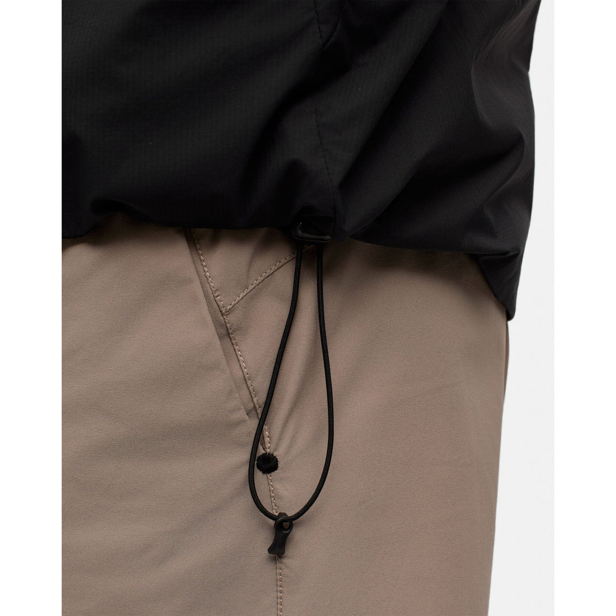 Close-up of the black recycled nylon hem of a Men’s Level Alpha Jacket Black Beauty, featuring an adjustable drawstring cord with a plastic toggle.
