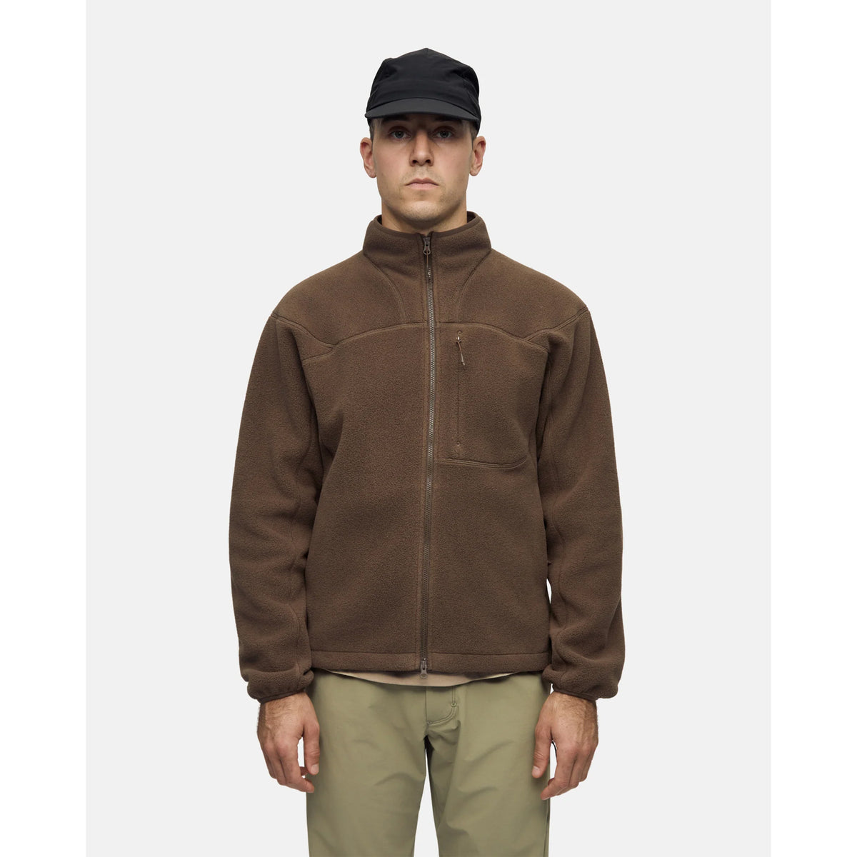 A person wearing an olive cap and pants with a brown Men’s Loam Fleece Jacket Slate Black that features a chest pocket.