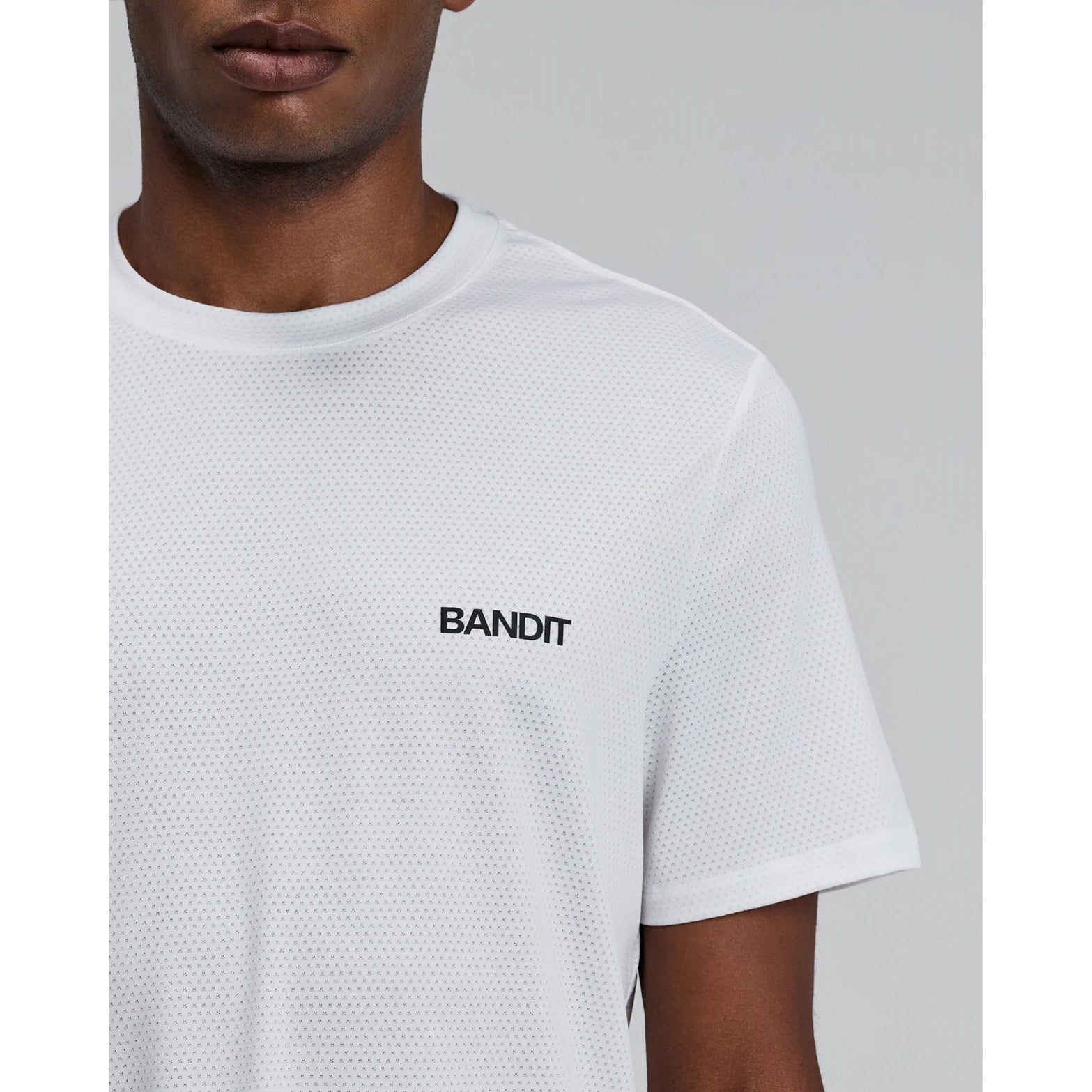 Bandit Micromesh Run Tee men's in White — closeup showing dyed-to-match reflective graphic detail at centre front on white Micromesh™ breathable fabric