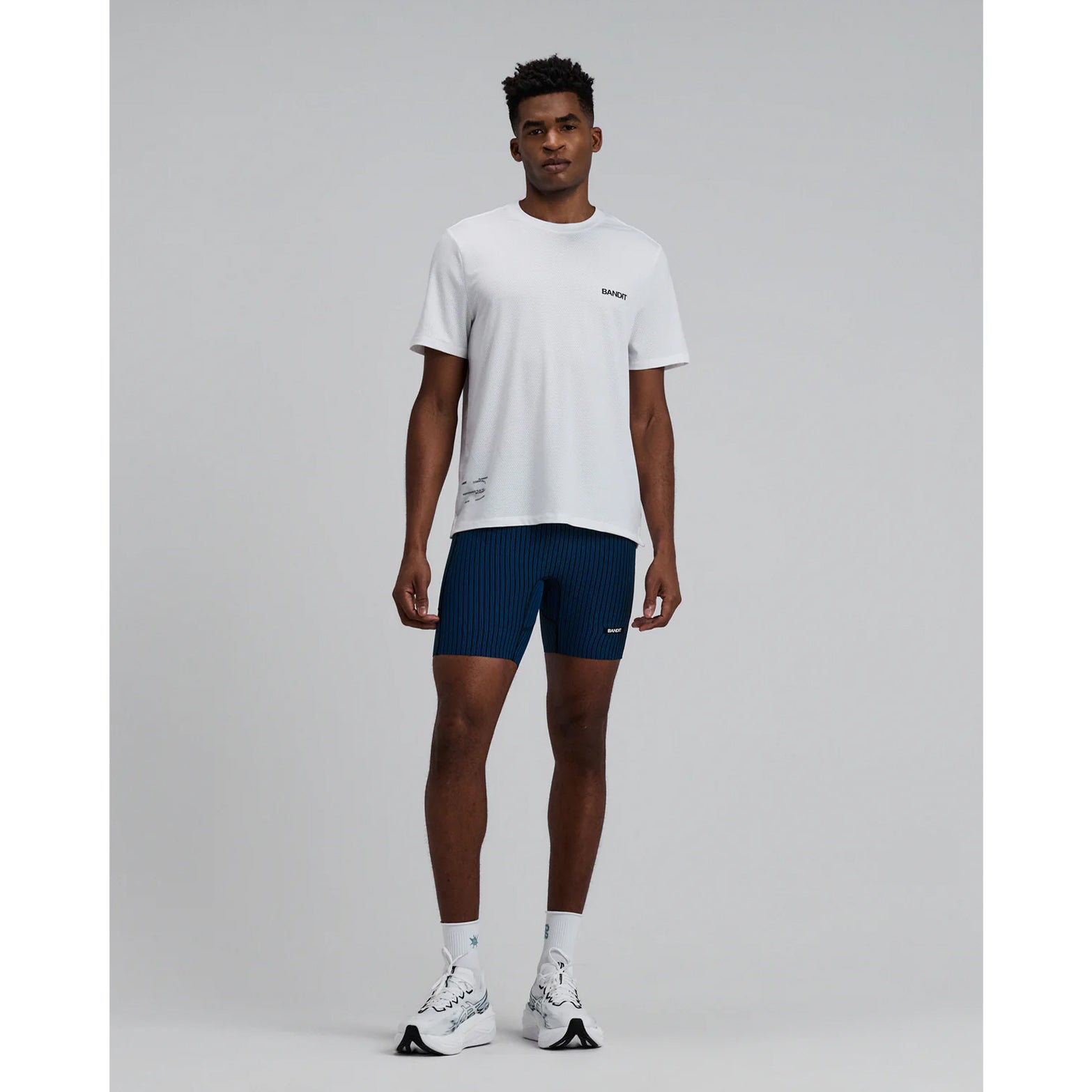 Bandit Micromesh Run Tee men's in White — full body front view worn on model showing relaxed fit silhouette, Micromesh™ fabric drape and dyed-to-match reflective graphic at centre front