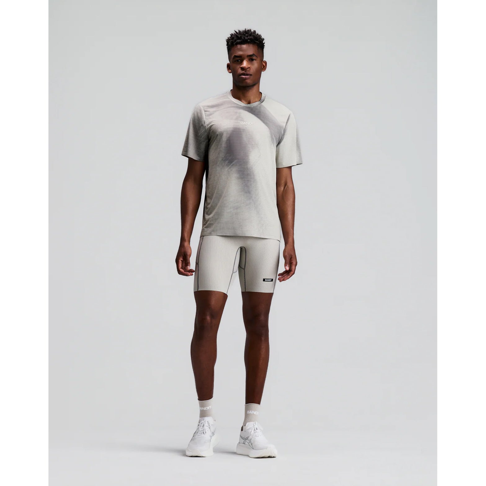 Men's Bandit Specter Performance Tee Slate Plaster front full body view on male runner showing relaxed fit with lightweight Specter fabric and ultra-breathable anti-cling construction for training and everyday running