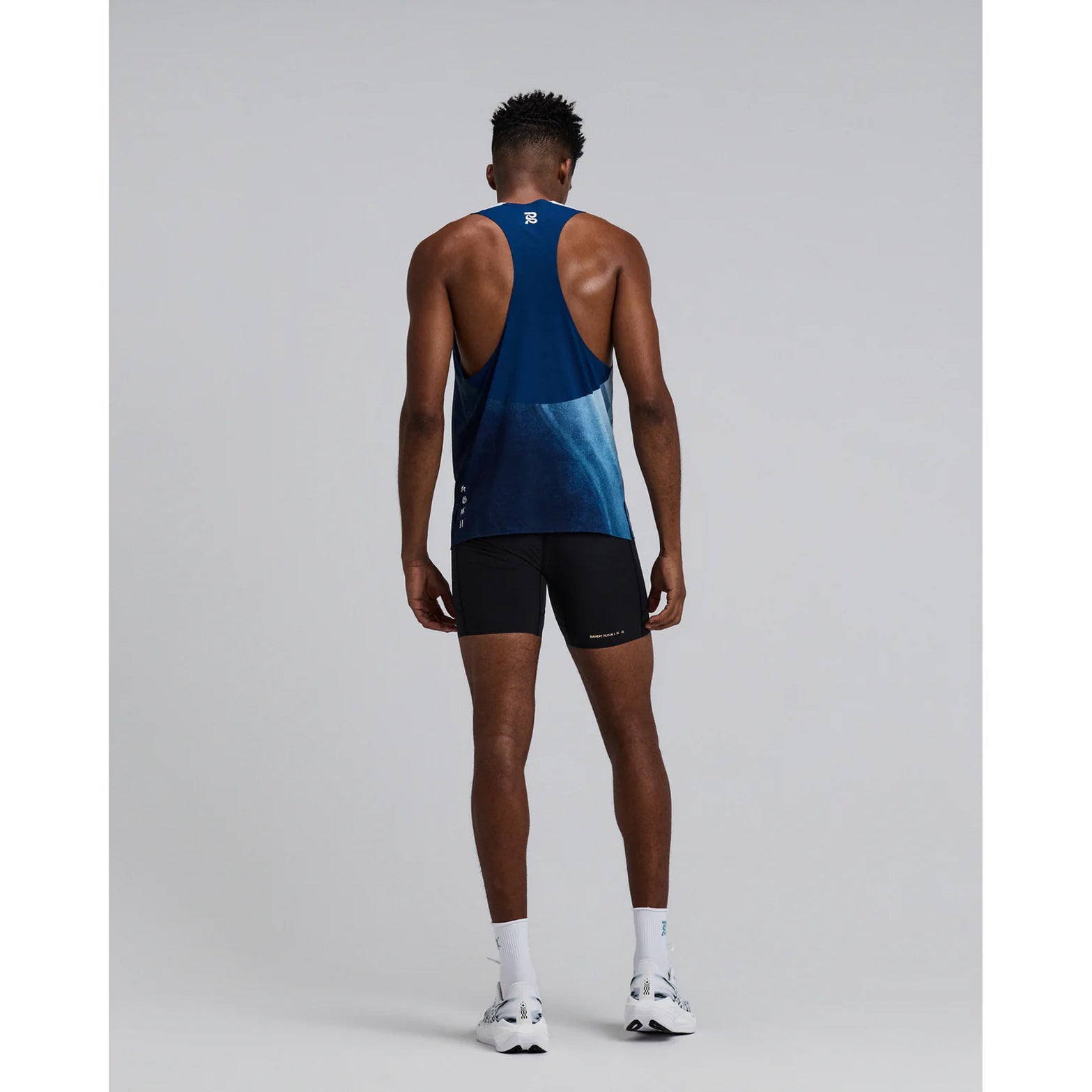 Bandit Specter Race Singlet men's in Undertow Ink Blue Multi — full body back view worn on model showing deep racerback construction, side slits and undertow ink blue multi Specter™ fabric in motion