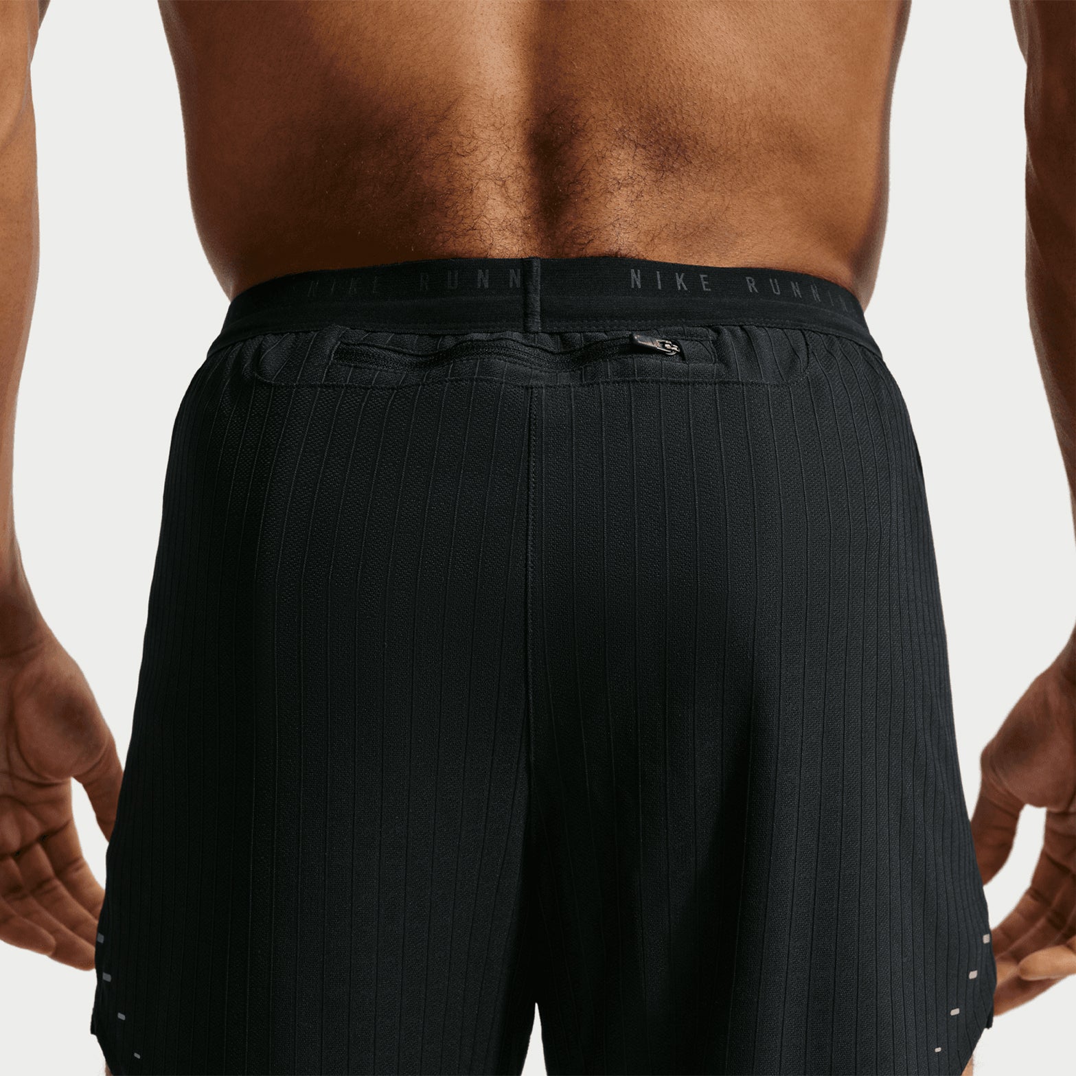 Men's Nike Stride Aero-FIT 5 Inch Shorts Black back view on male runner showing zippered phone pocket with Aero-FIT breathability technology and reflective details for running