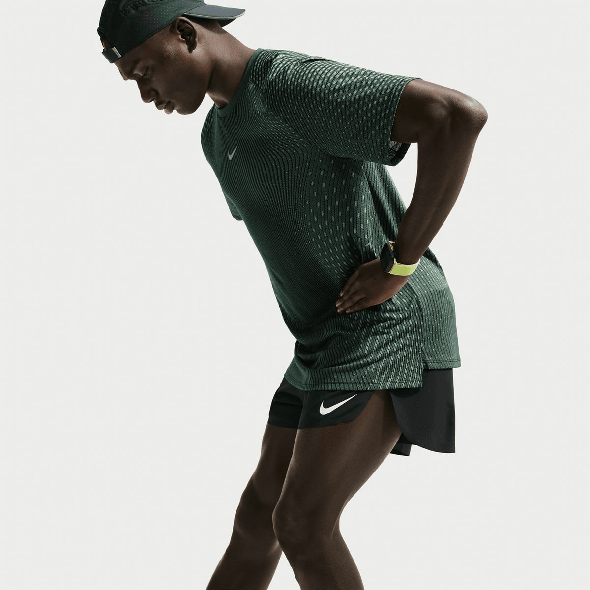 Men's Nike Stride Aero-FIT Running Tee Black Light Green Spark side view on male runner showing side hem vents with lightweight Aero-FIT construction for unrestricted movement and airflow during running