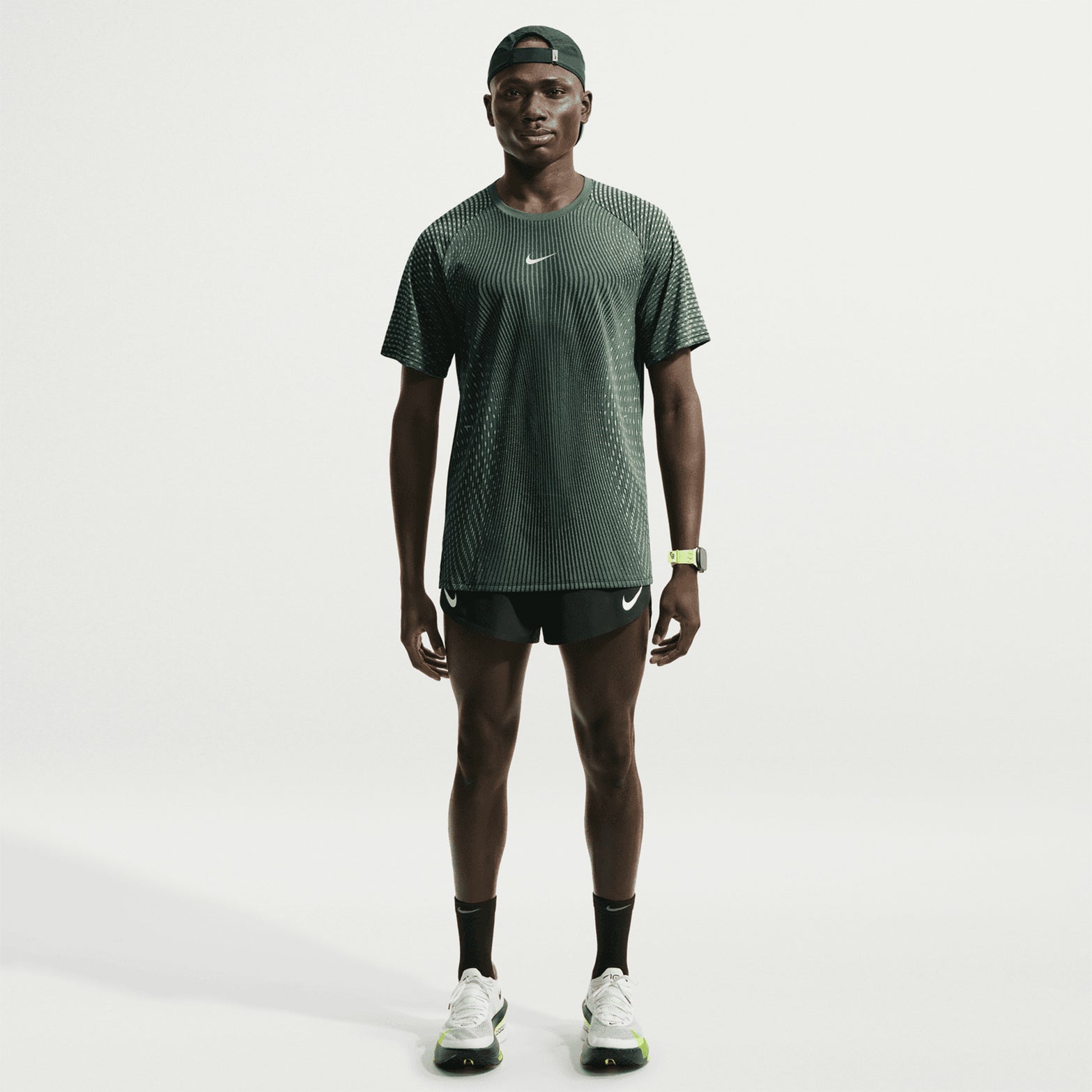 Men's Nike Stride Aero-FIT Running Tee Black Light Green Spark full body view on male runner showing lightweight knit with strategic mesh zones and side hem vents for maximum breathability and unrestricted movement
