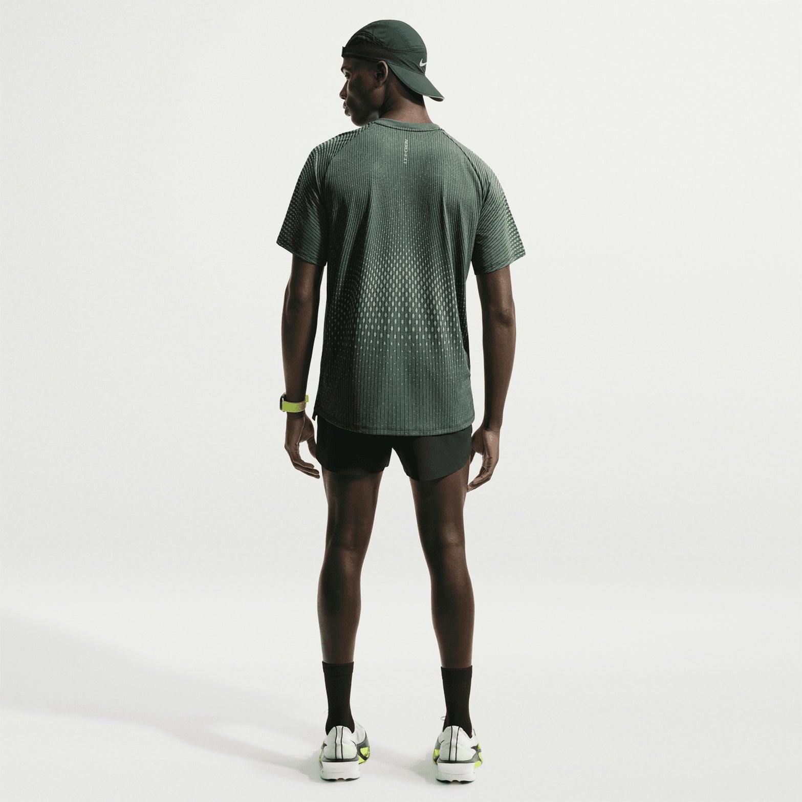 Men's Nike Stride Aero-FIT Running Tee Black Light Green Spark full body back view on male runner showing strategic back mesh zones with Aero-FIT technology for maximum breathability and active cooling during warm weather training