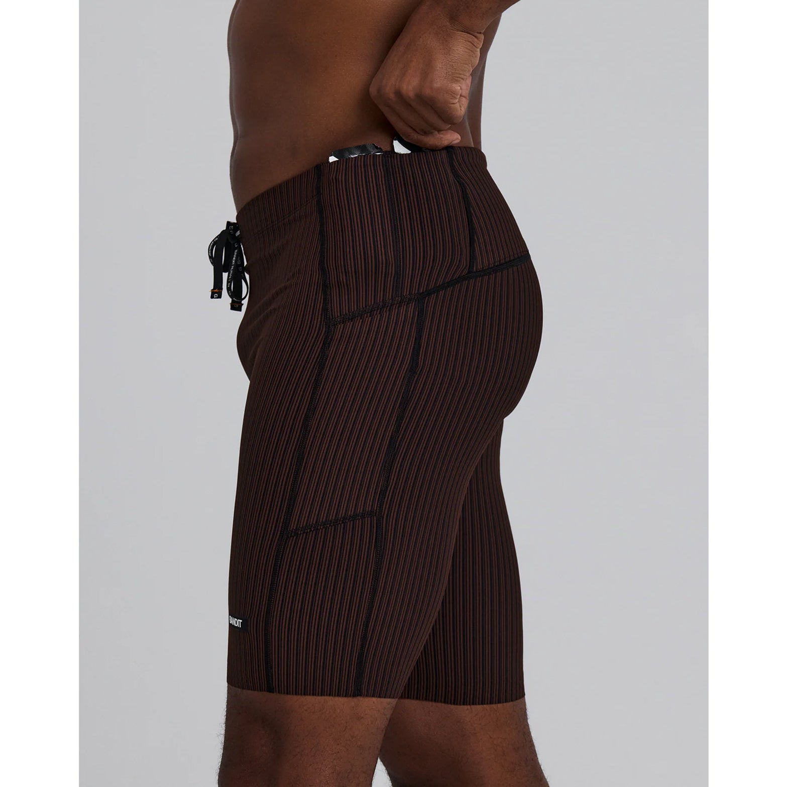 Bandit Striped Cadence 7 Pocket Half Tights men's in Cacao / Black — side view worn on model showing compression fit silhouette, GripDot™ hem detail and cacao and black Striped Cadence™ ribbed knit profile