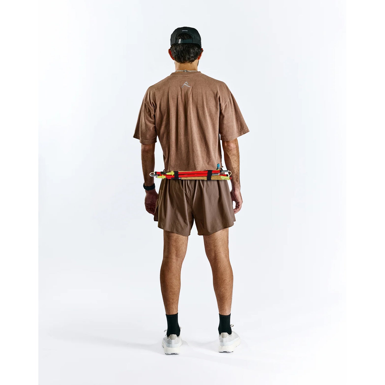 Raide TrailTech Short men's in Bark — full body back view worn on model showing large rear pocket placement, zippered pocket detail and Toray DotAir outer construction in motion on trail