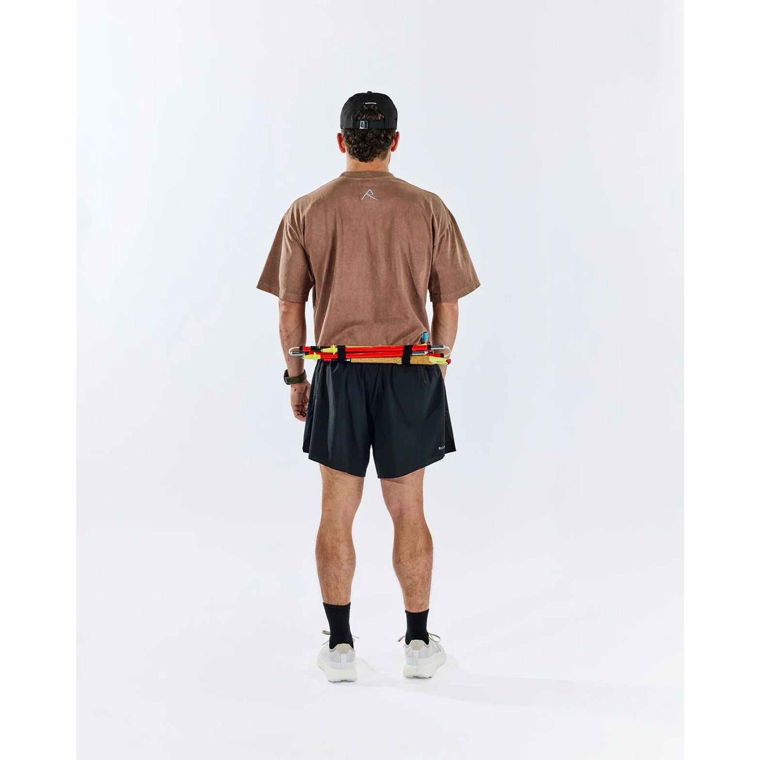 Raide TrailTech Short men's in Black — full body back view worn on model showing large rear pocket placement, zippered pocket detail and Toray DotAir outer construction in motion on trail