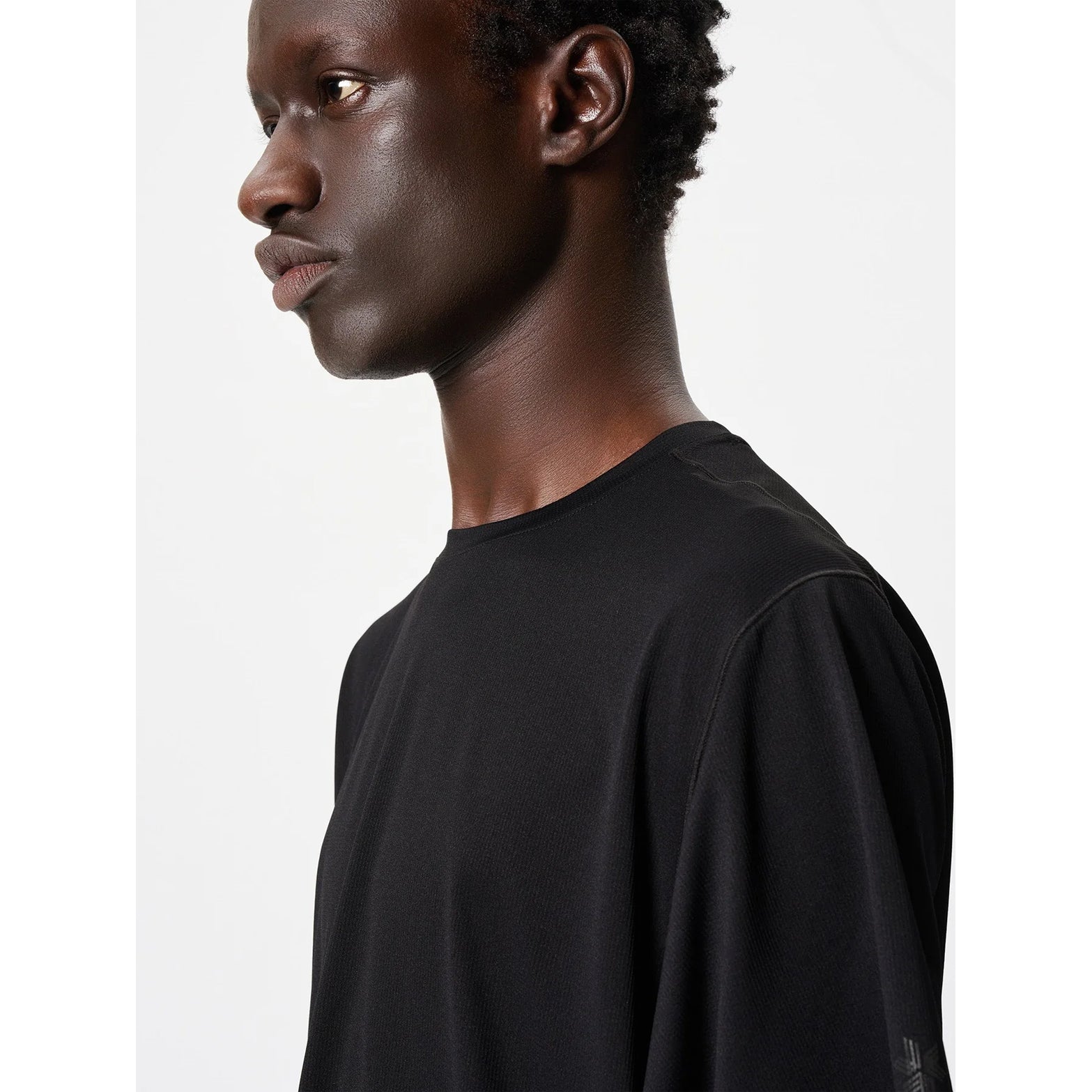 Goldwin Men's WF-Dry Tee Black side close-up showing modified raglan sleeves with forearm wedges for natural arm movement during running and hiking