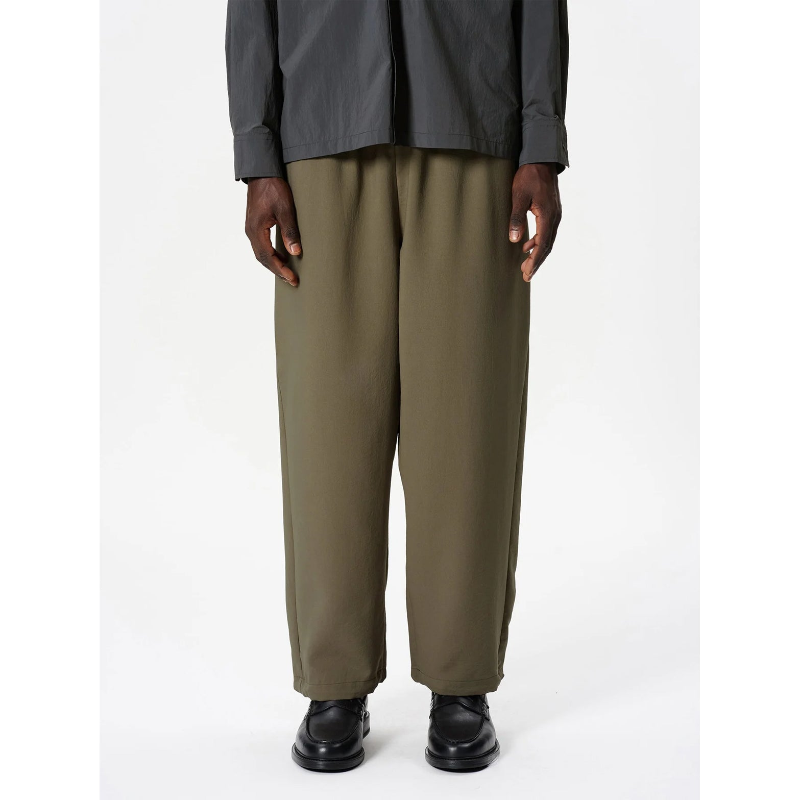 Goldwin Men's Wide Ankle Easy Pants Sand Land front view on male model showing wide adjustable silhouette with drawstring hem and 2-layer softshell construction with UV protection