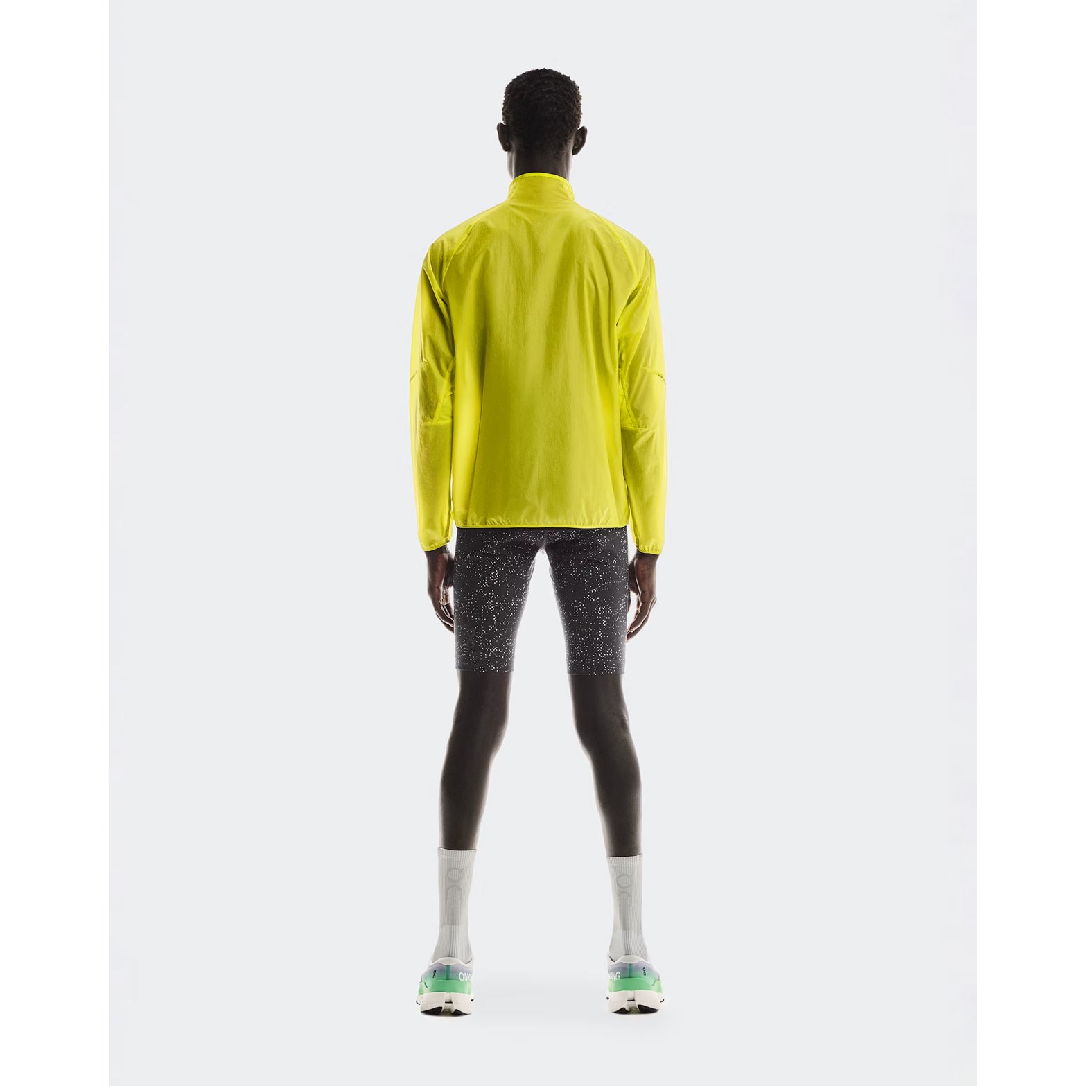 Men's On Zero Jacket Lime full body back view on male runner showing breathable lightweight construction with reflective elements for low-light visibility
