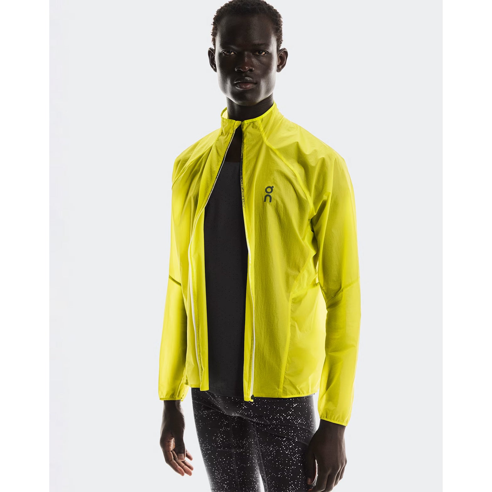 Men's On Zero Jacket Lime front view on male runner showing lightweight windproof construction with water-repellent surface and reflective elements