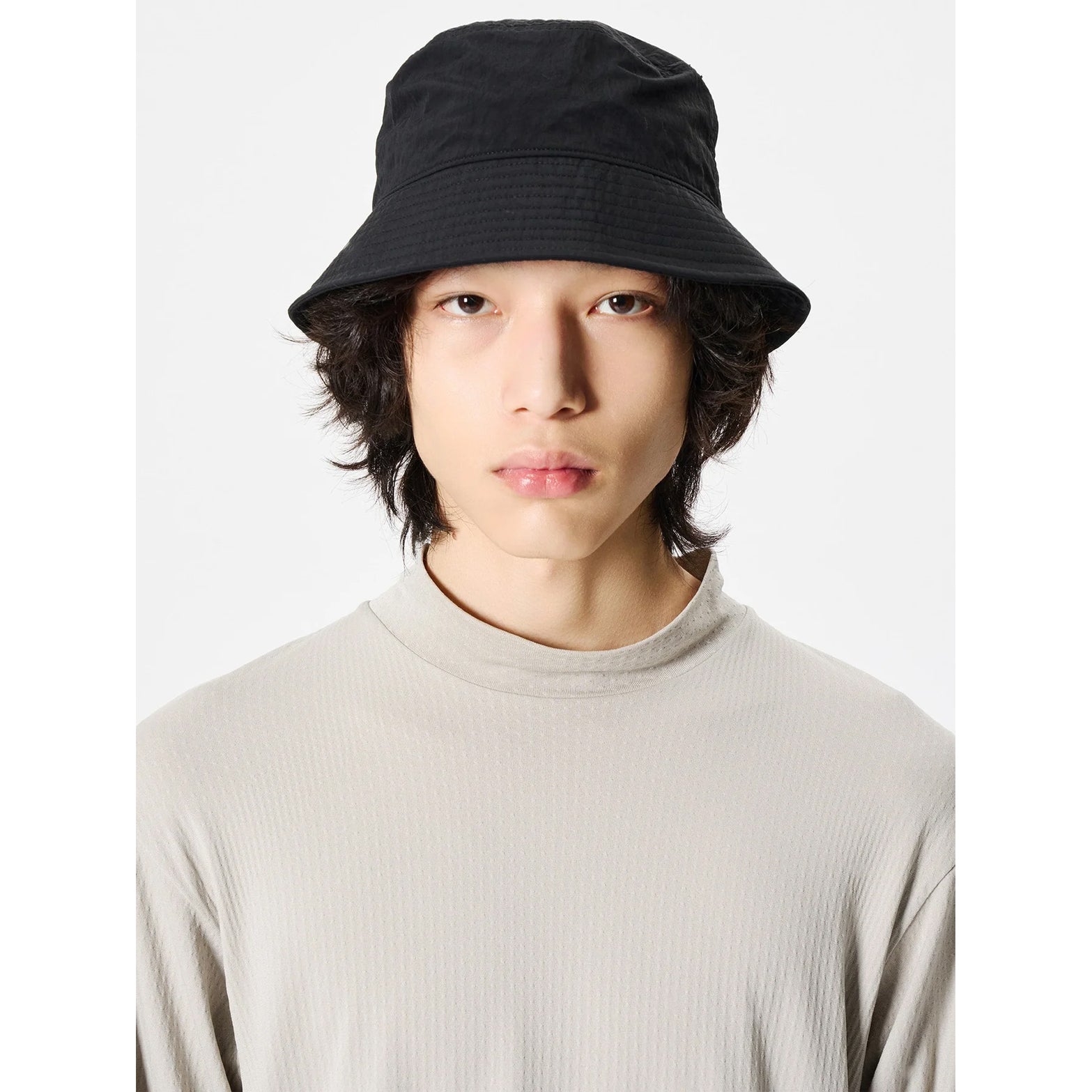Goldwin Nylon Bucket Hat Black front view on male model showing structured bucket hat design with densely woven recycled nylon and adjustable back fit