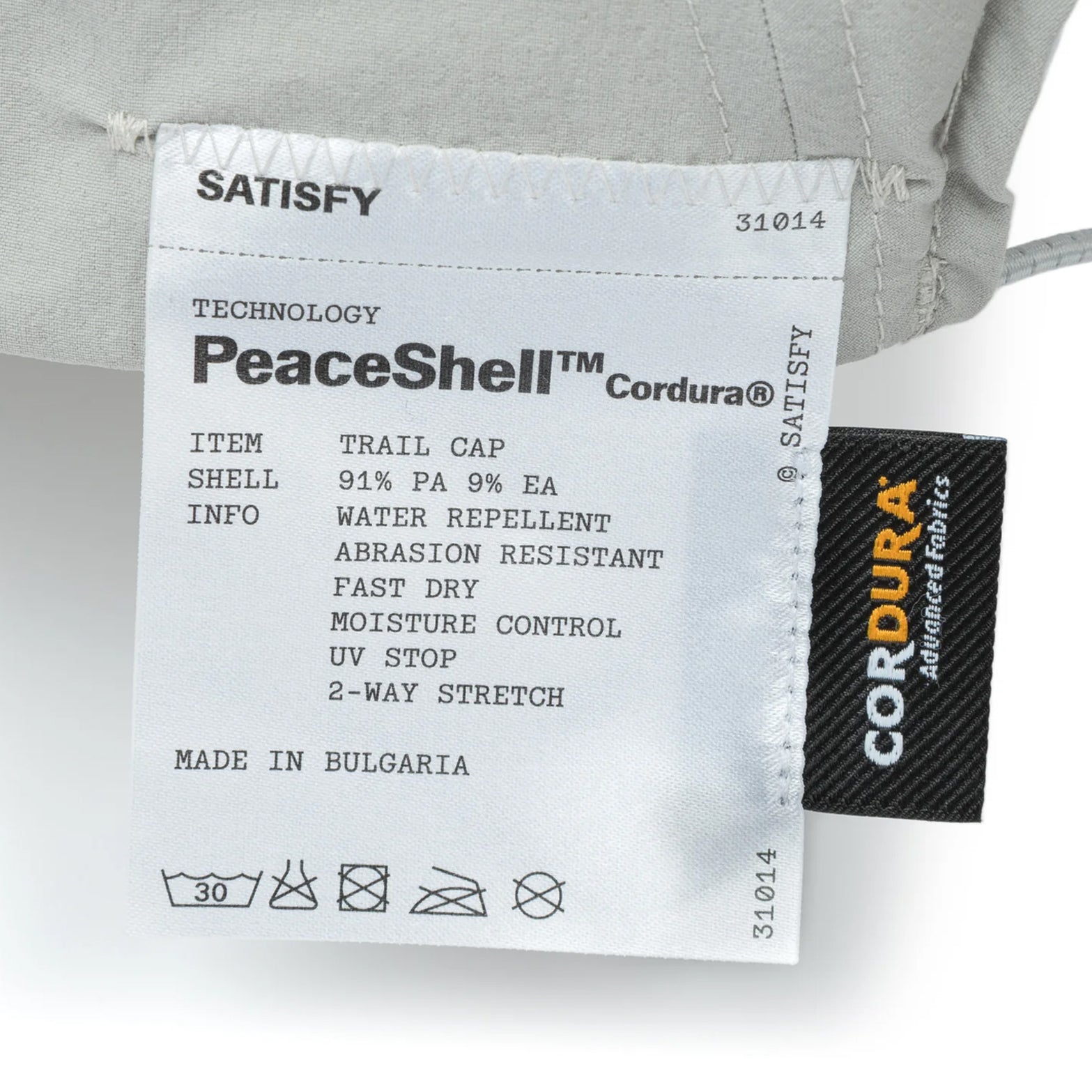 Satisfy PeaceShell Cordura Trail Cap in Light Grey — closeup showing fully detachable exterior care label on light grey PeaceShell™ Cordura construction