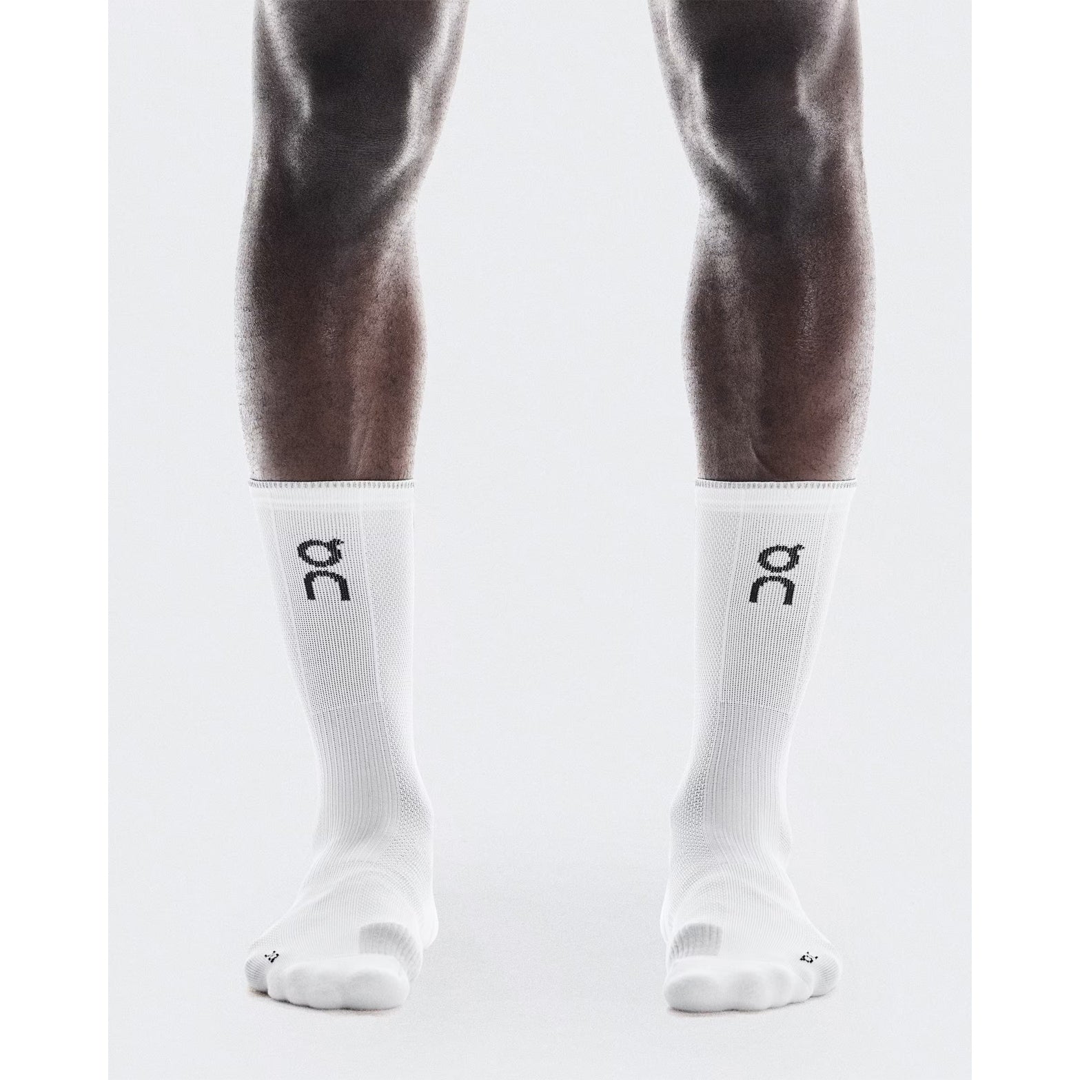 On Performance Run Sock High White Glacier front view on runner showing contrast logo and reflective yarn