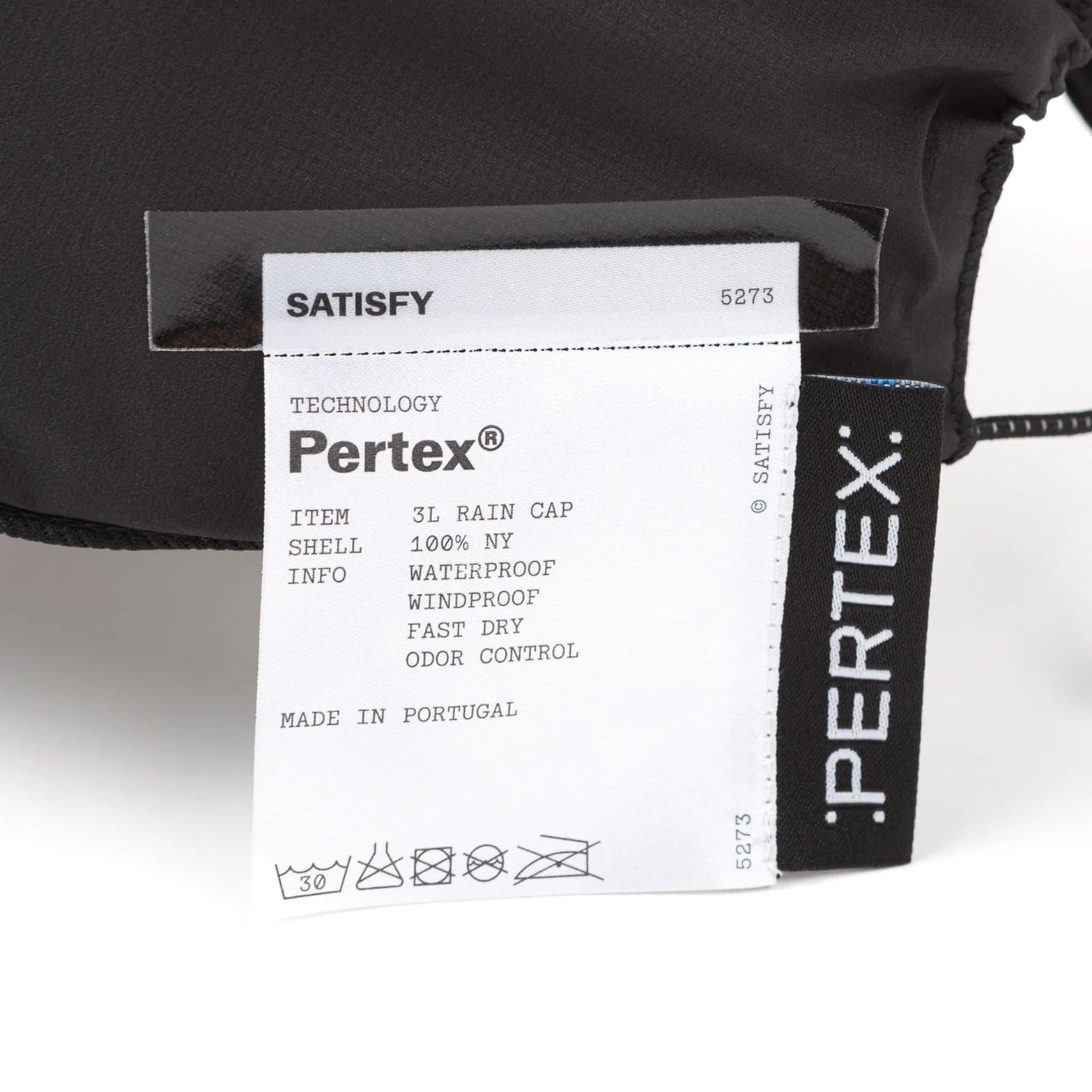 Satisfy Pertex® 3L Rain Cap in Black — closeup showing fully detachable exterior care label on black Pertex® Shield Air three-layer nano-ripstop construction